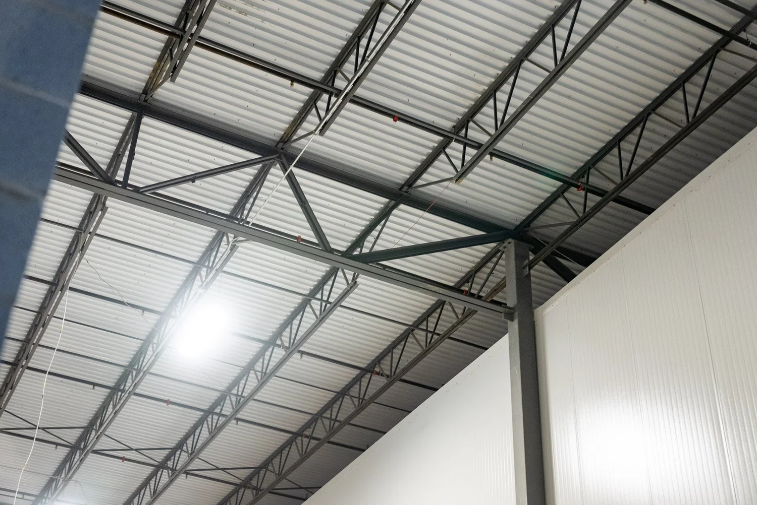 Insulated metal panel walls rising to the steel roof framing inside a building