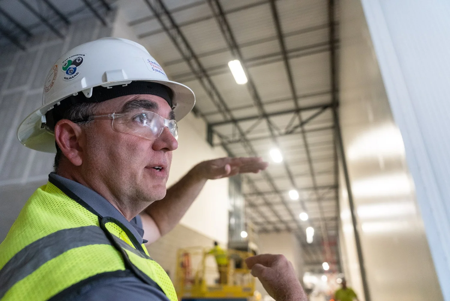 Crew member in a hard hat pointing out work inside a building