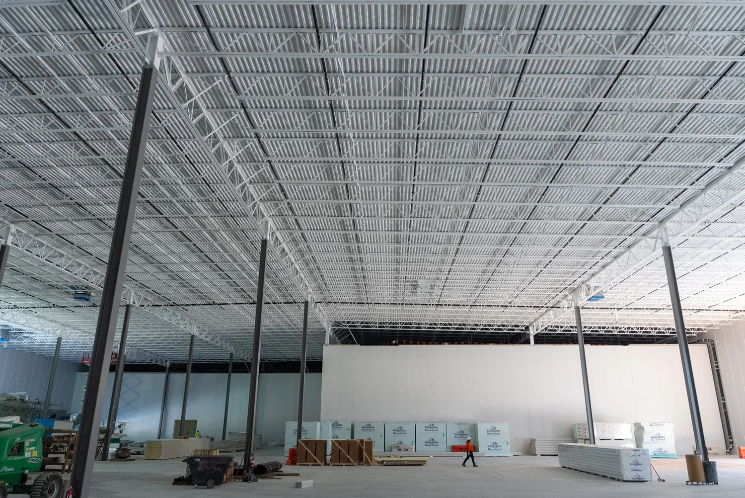Interior of a large cold storage building under construction with steel roof framing