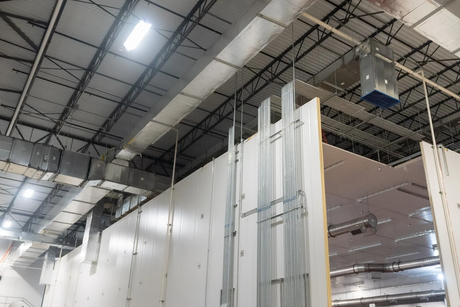 Insulated metal wall panels being installed inside a large warehouse