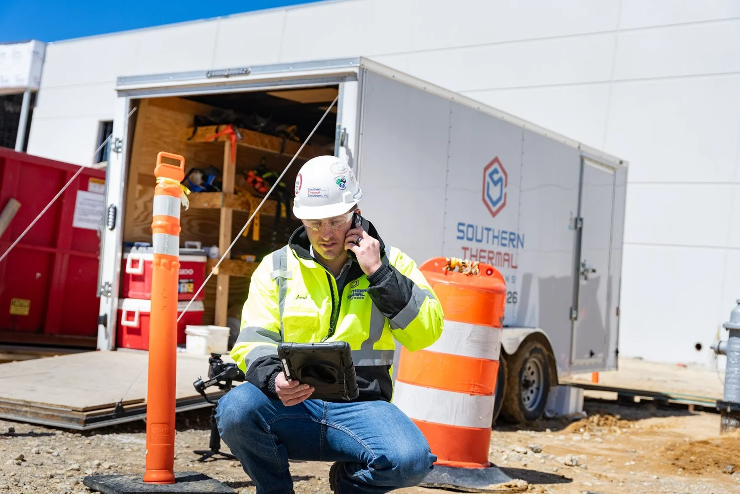 Crew member in a hard hat using a tablet outside a Southern Thermal Solutions job trailer