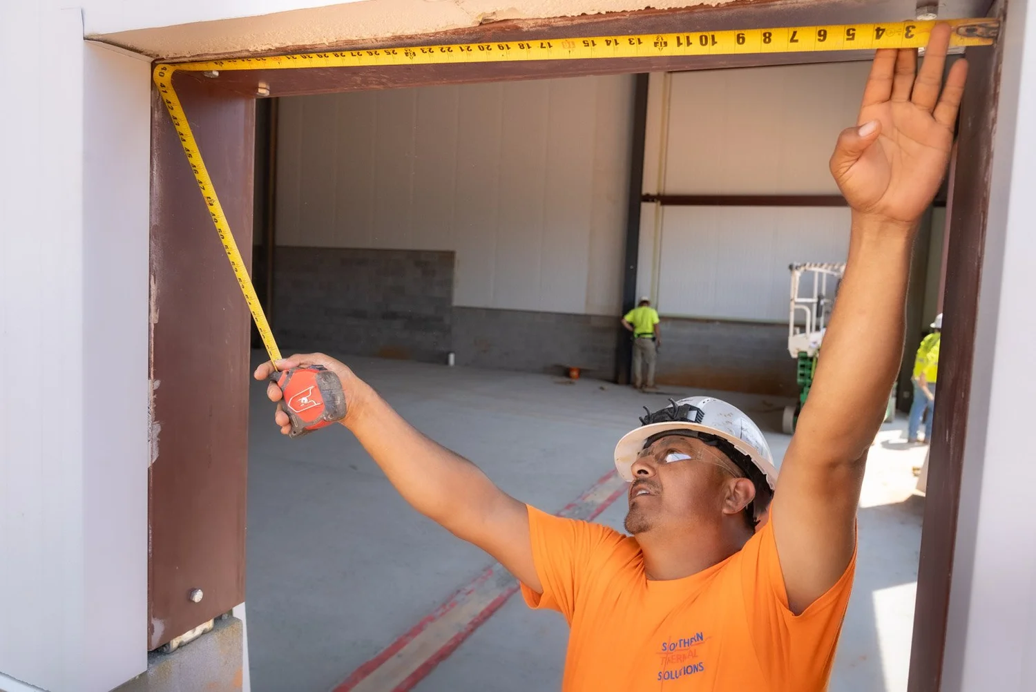 Crew member measuring a door opening in an insulated panel wall