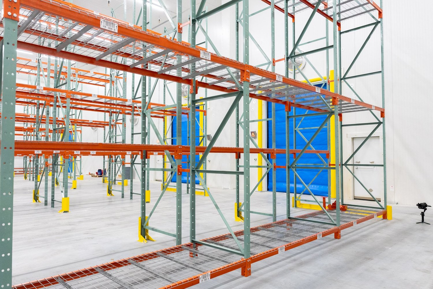 Pallet racking in front of a blue insulated door in a cold storage room