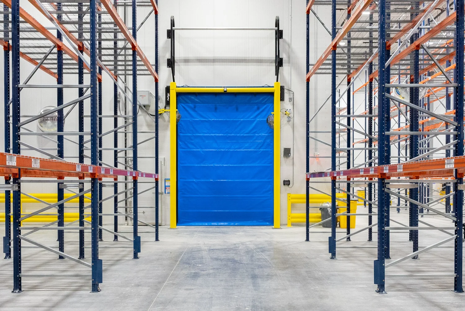 Blue insulated cold room door at the end of an aisle of pallet racking
