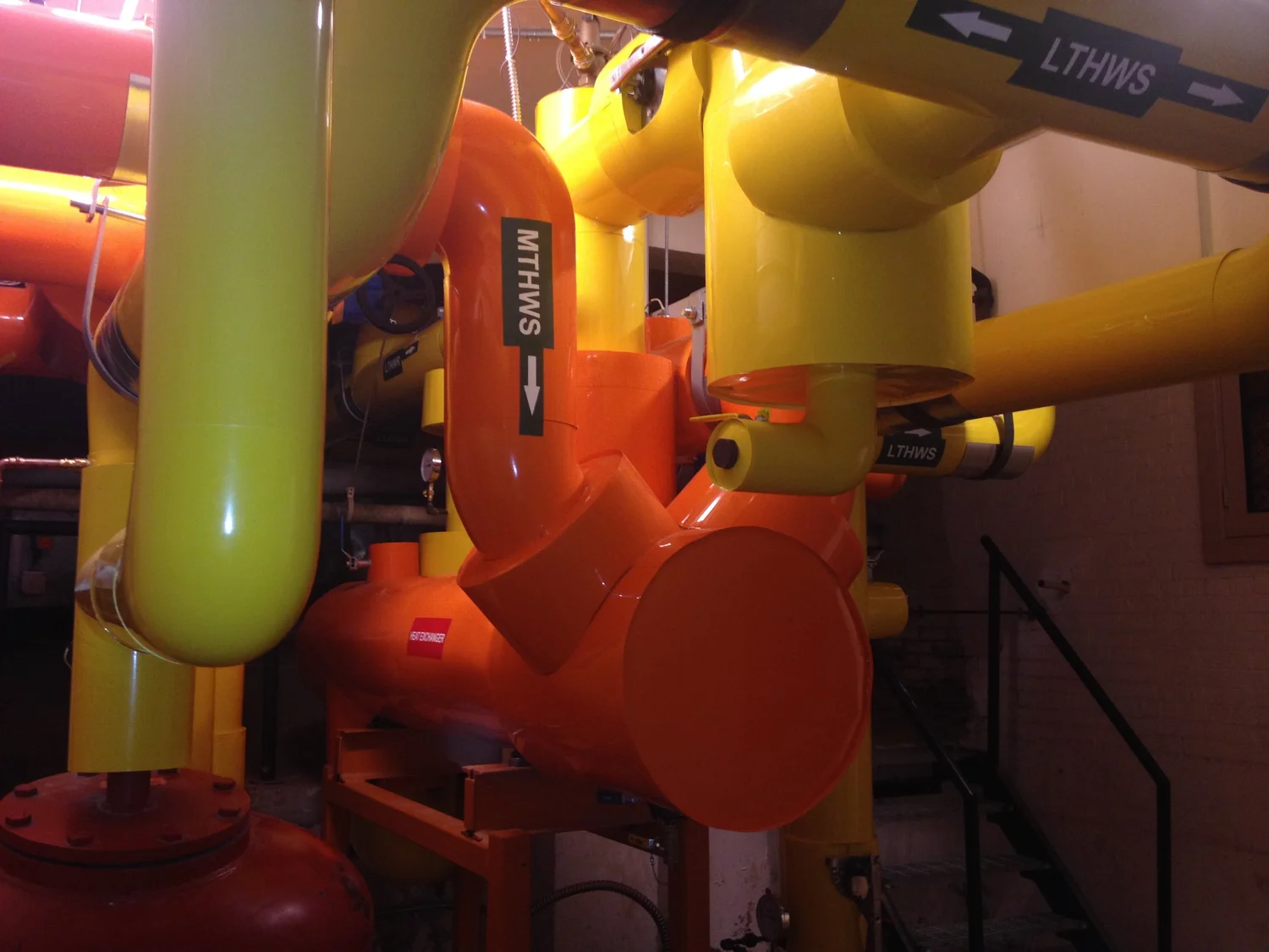 A network of colorful pipes, including yellow and orange sections, with labels such as 'LTHWS' and 'SWHS' in an industrial setting.