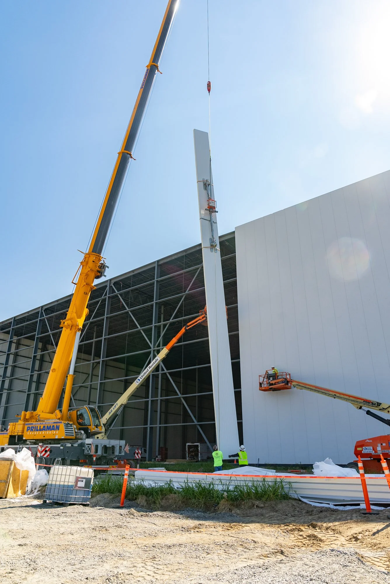 Crane lifting a tall insulated metal panel into place on the FreezePak building