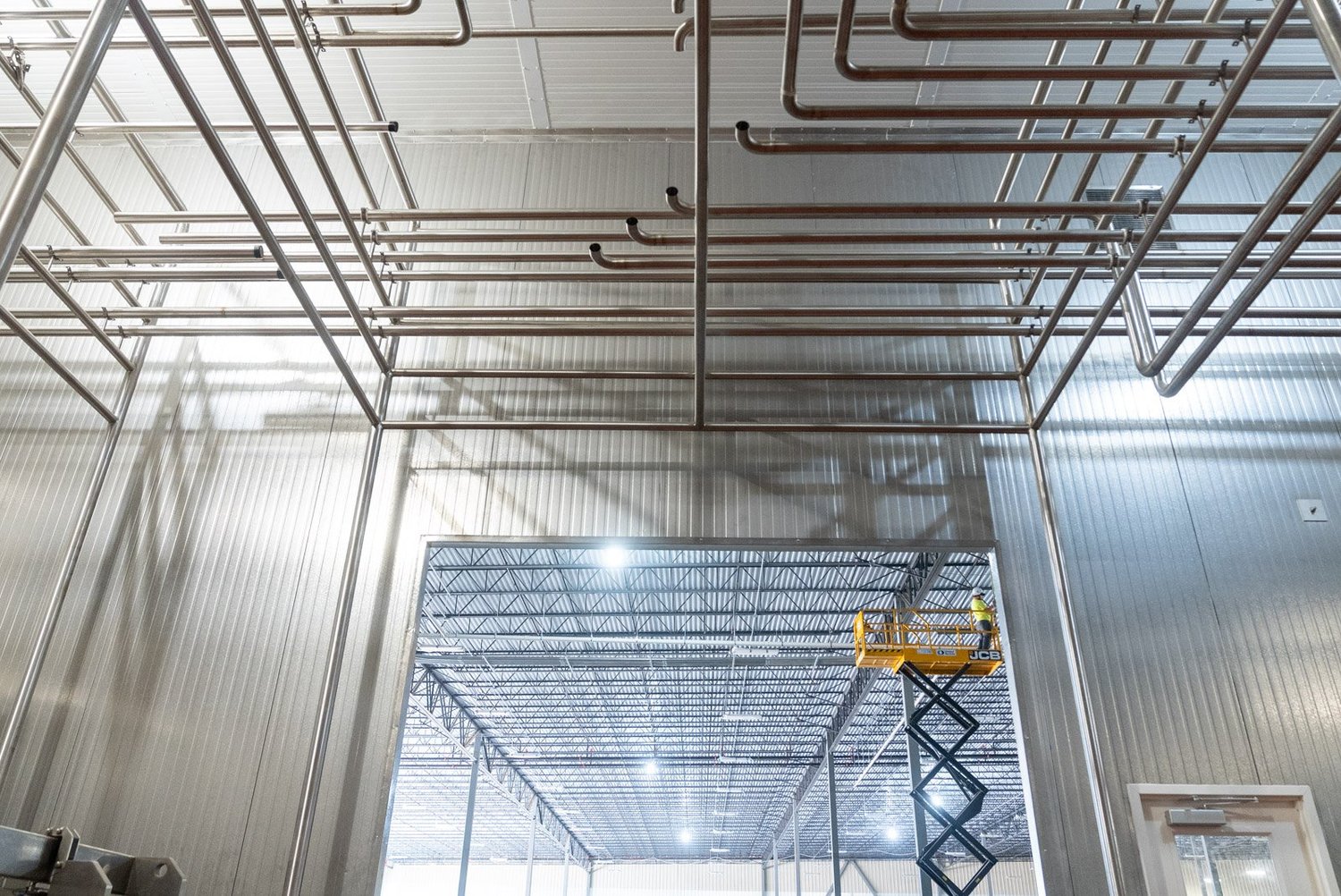 Tall insulated metal panel walls and ceiling framing with a scissor lift inside a building