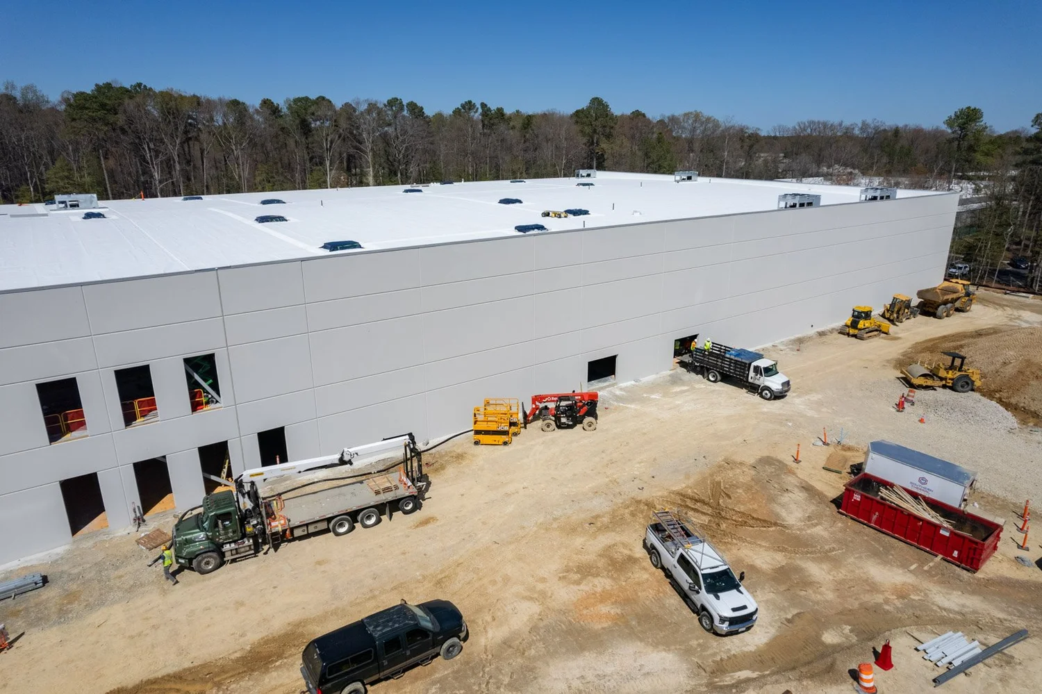 Aerial view of a large new warehouse under construction with trucks and equipment on site