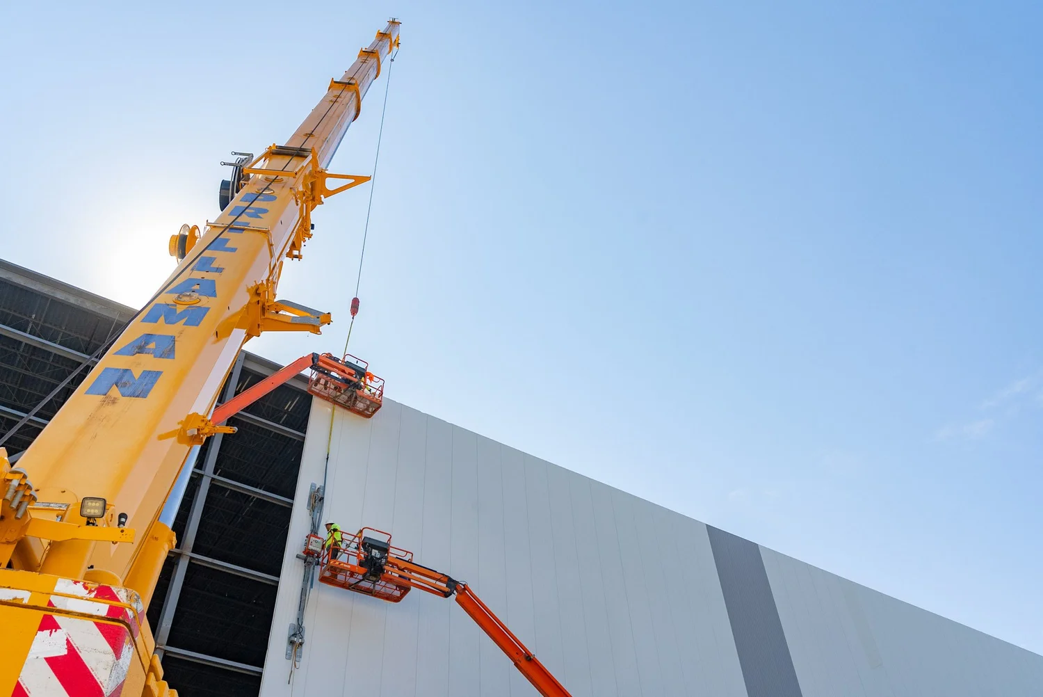 Crane and lift crew installing exterior insulated metal panels