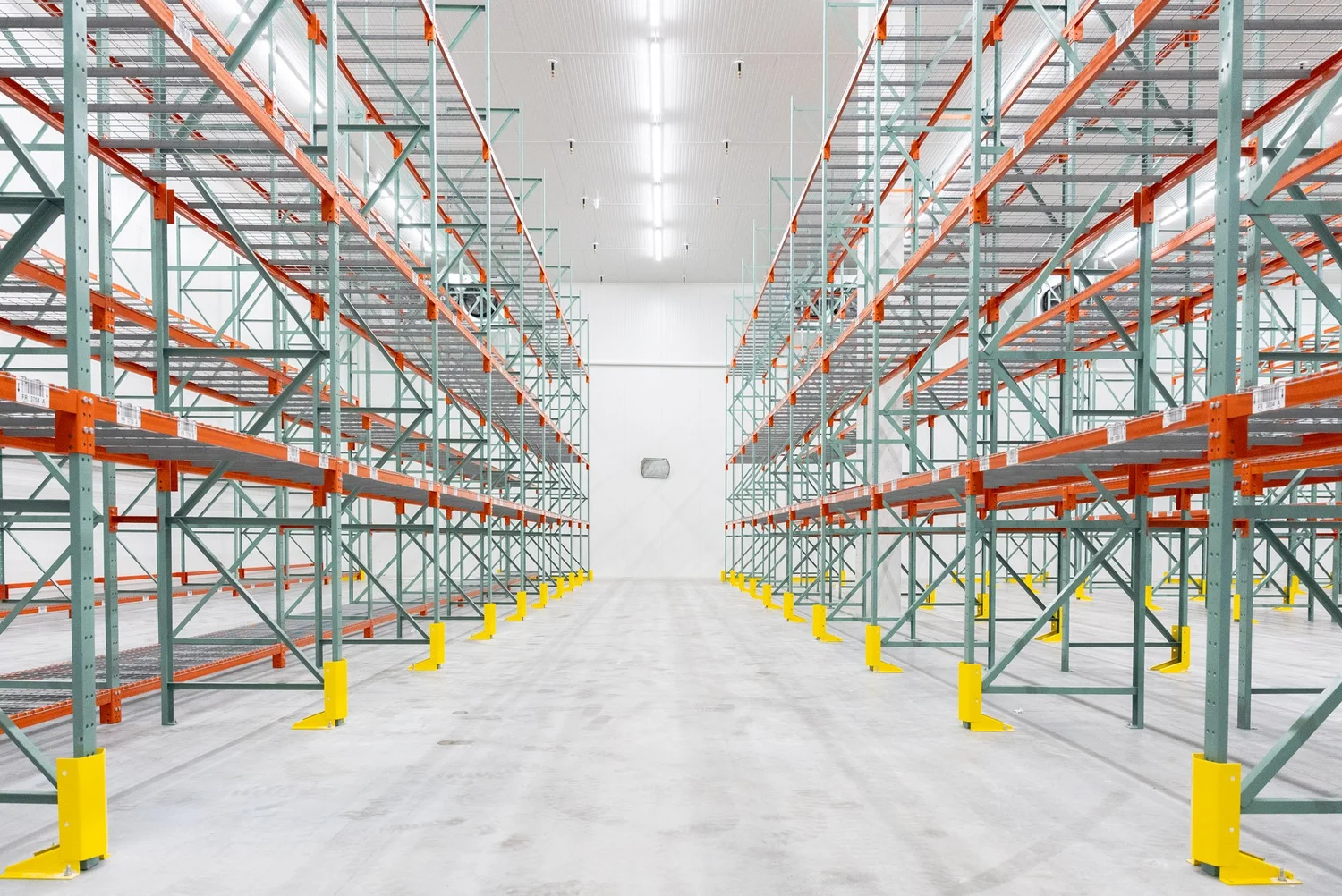 Aisle of pallet racking inside a cold storage building with white insulated panel walls