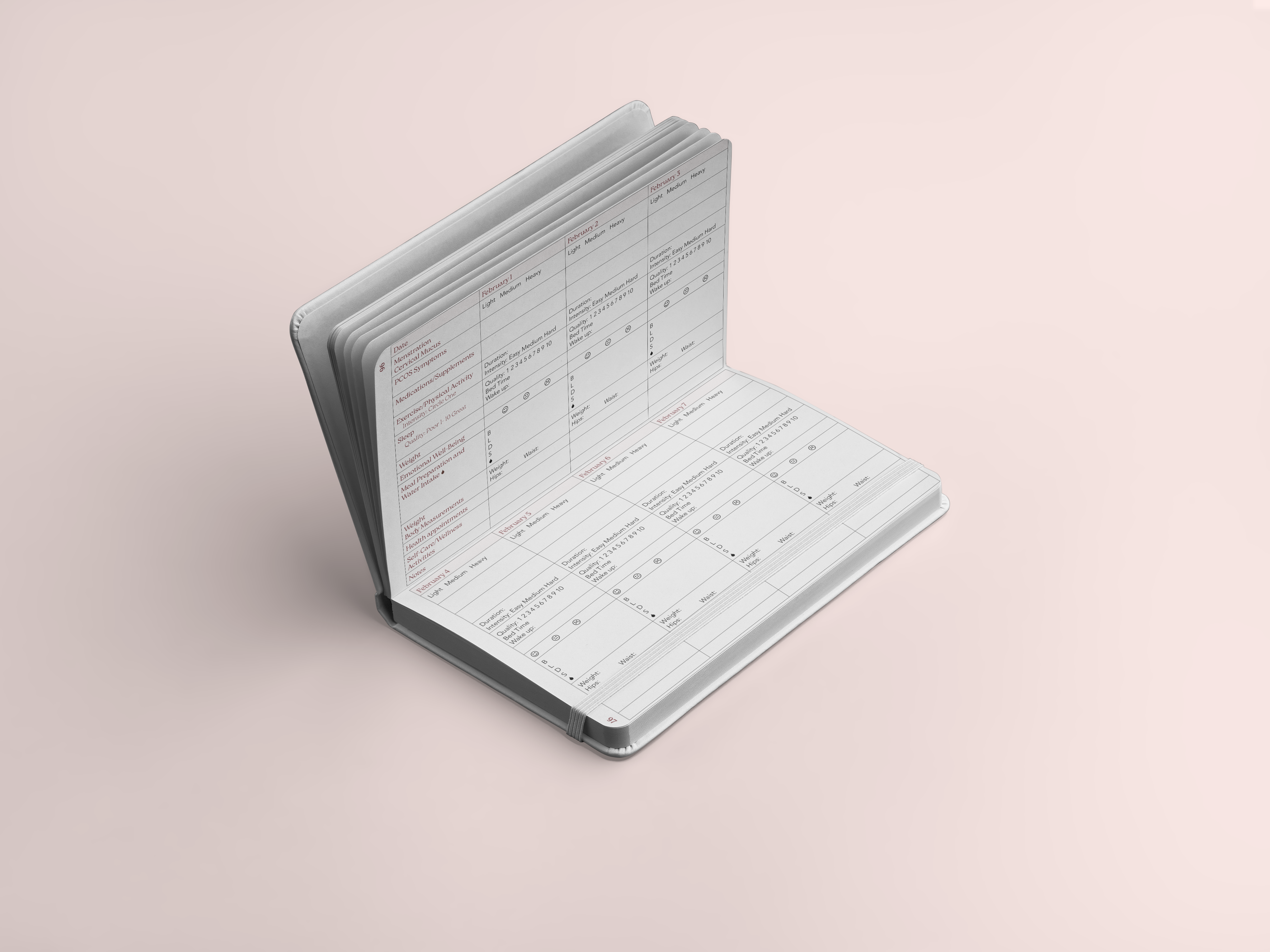 Open PCOS planner notebook displaying a symptom tracker chart, sitting on a pink surface.