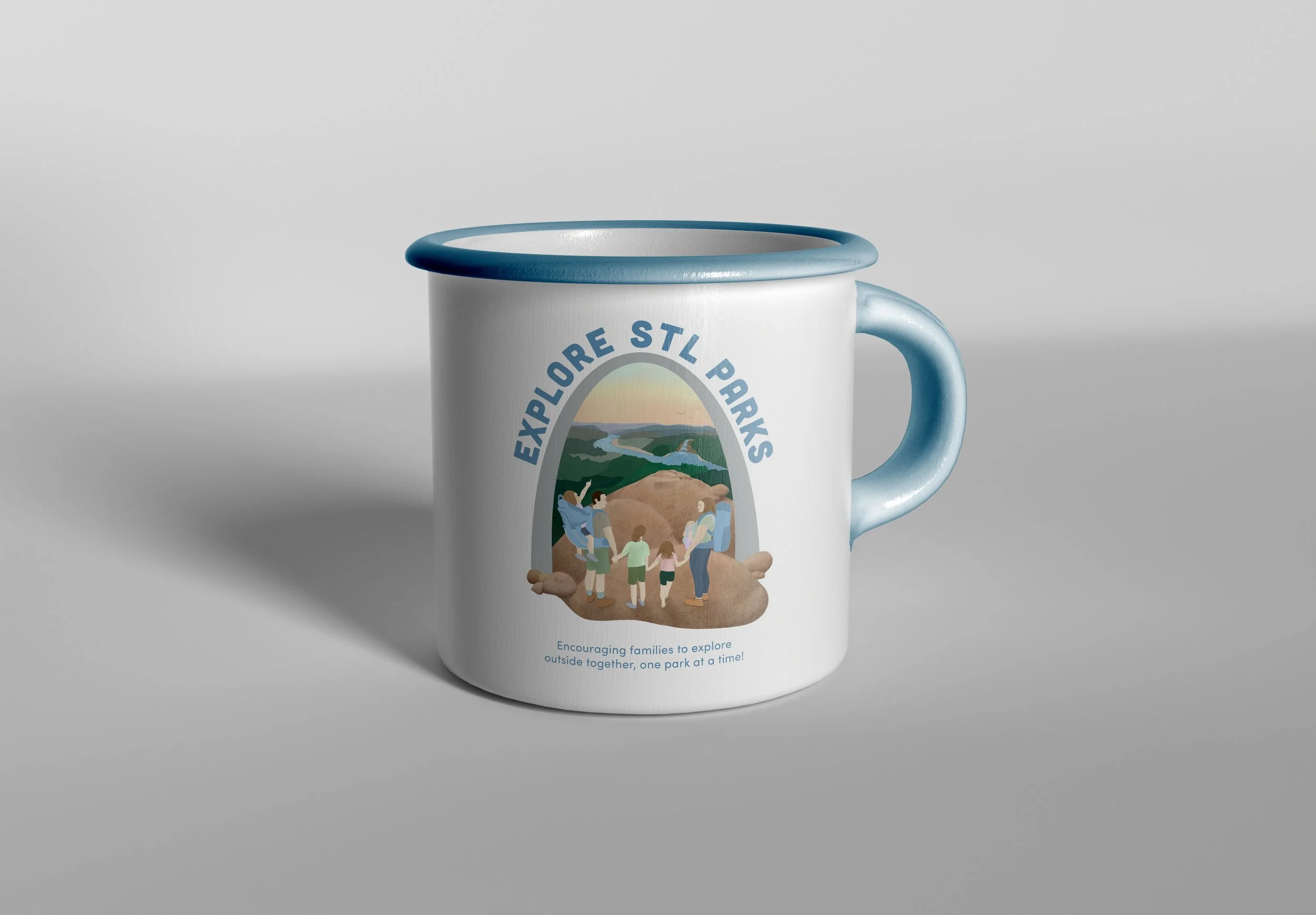 A white mug with a blue rim and handle, featuring a colorful illustration of a family exploring a park with a river and hills, and the text 'Explore STL Parks' created by Sophia Lappe.