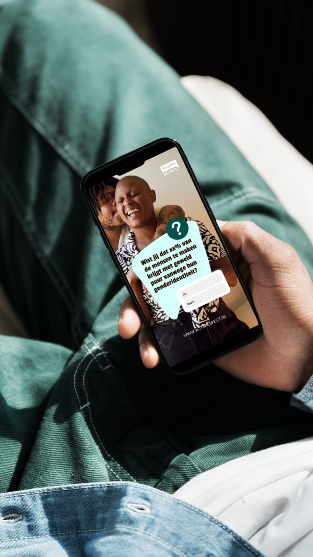 Een persoon houdt een smartphone vast die een foto toont van twee lachende mensen die elkaar knuffelen, met een vraag over genderidentiteit erop.