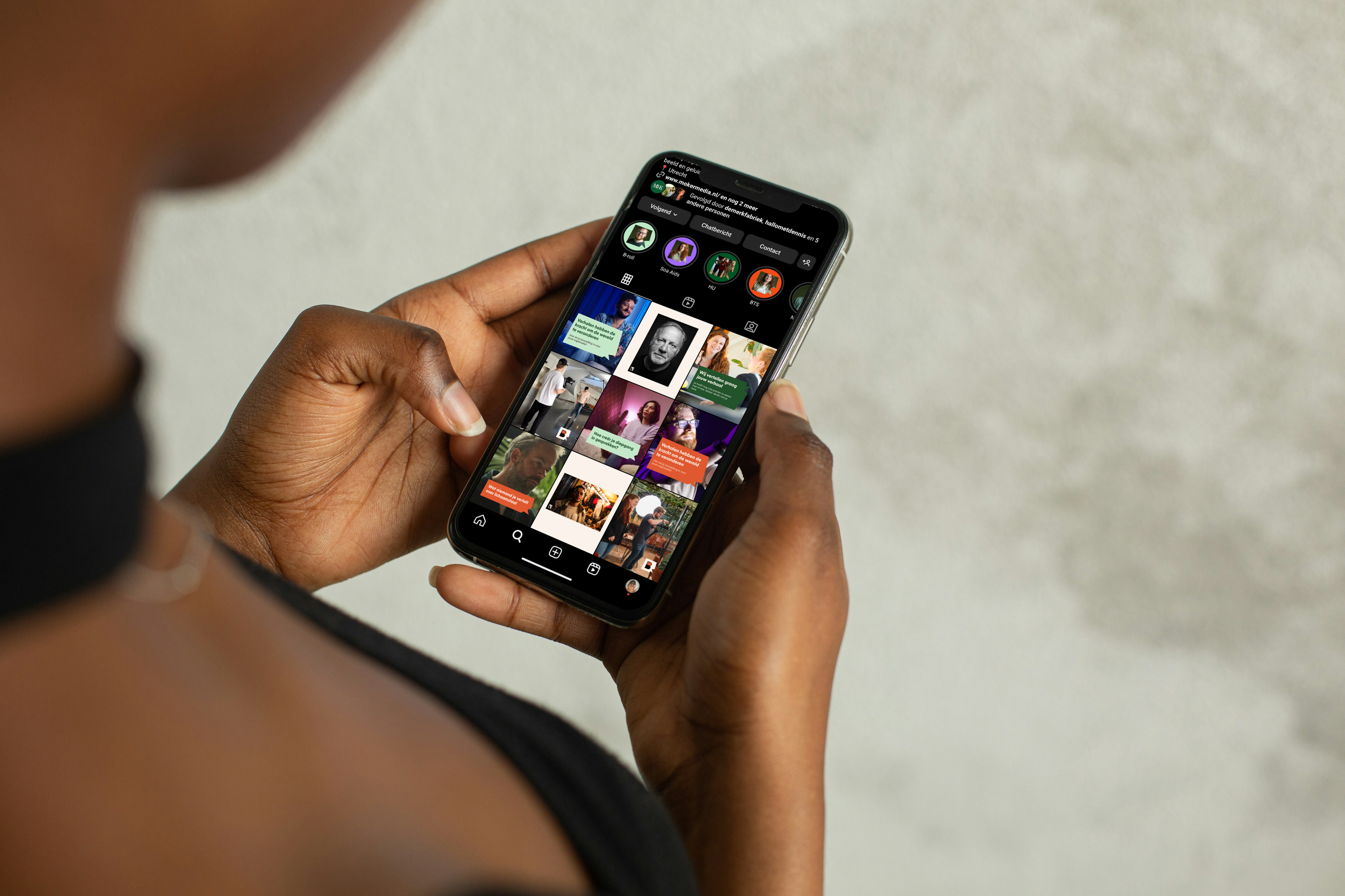 Vrouw houd mobiel vast dat het Instagram profiel toon van Moker Media in hun nieuwe huisstijl