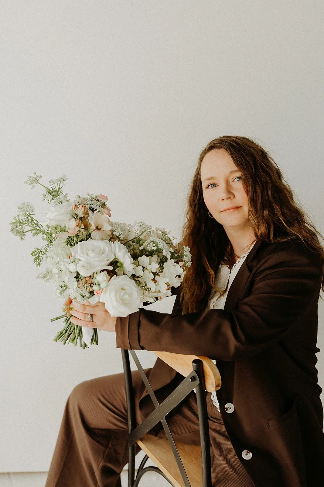 Rachell Vaden, owner and floral designer of Dahlias & Daisies in San Angelo, Texas, holding an artistic white garden-style bouquet.