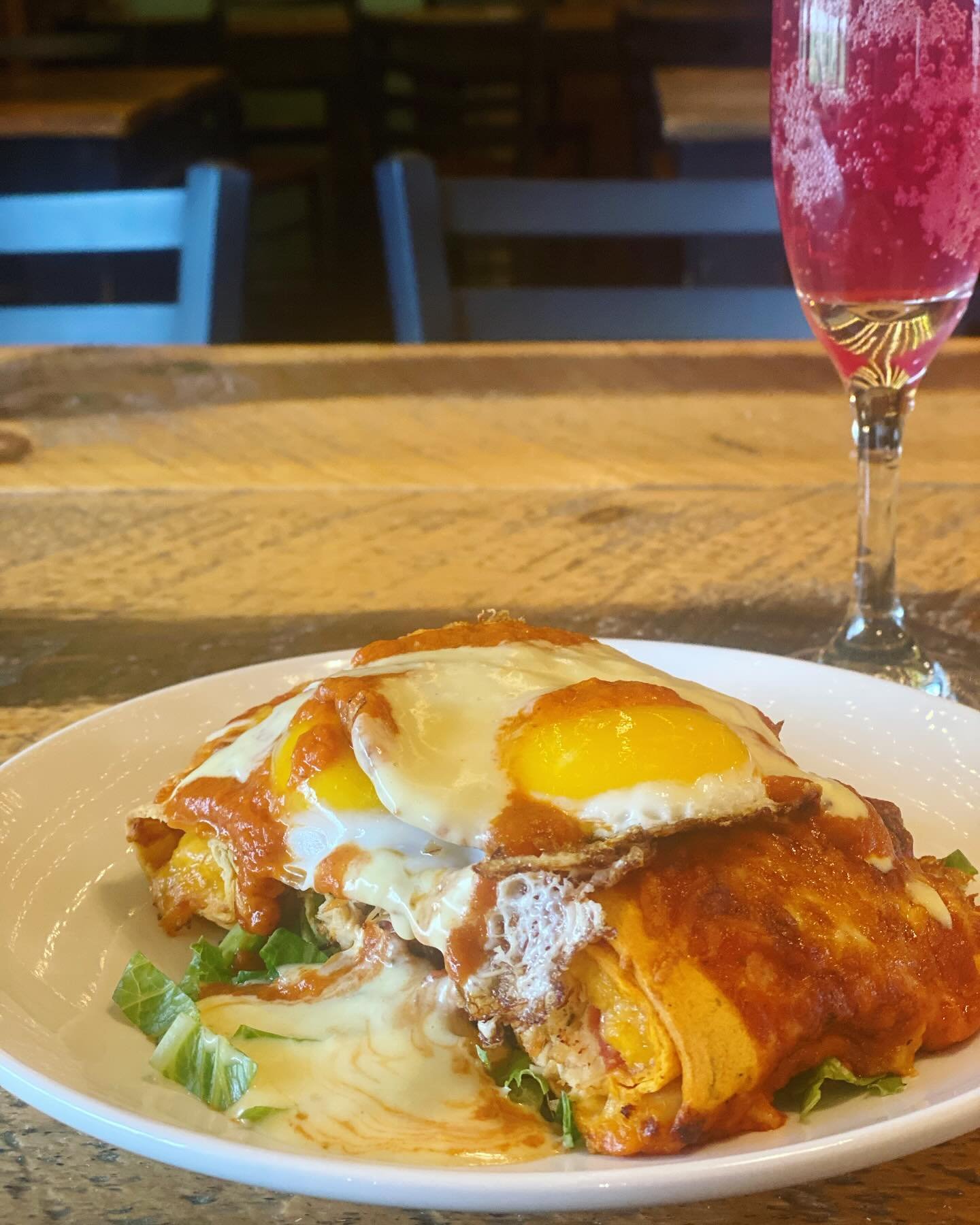 Sip happens, but brunch helps 🍳 🥂 

The whole enchilada 🌮 

Tender shredded chicken and a melty cheese blend snugly tucked in a tortilla! Topped with a dollop of creamy sour cream, two sunny side eggs, a zesty tomato ranchero sauce, and a luscious