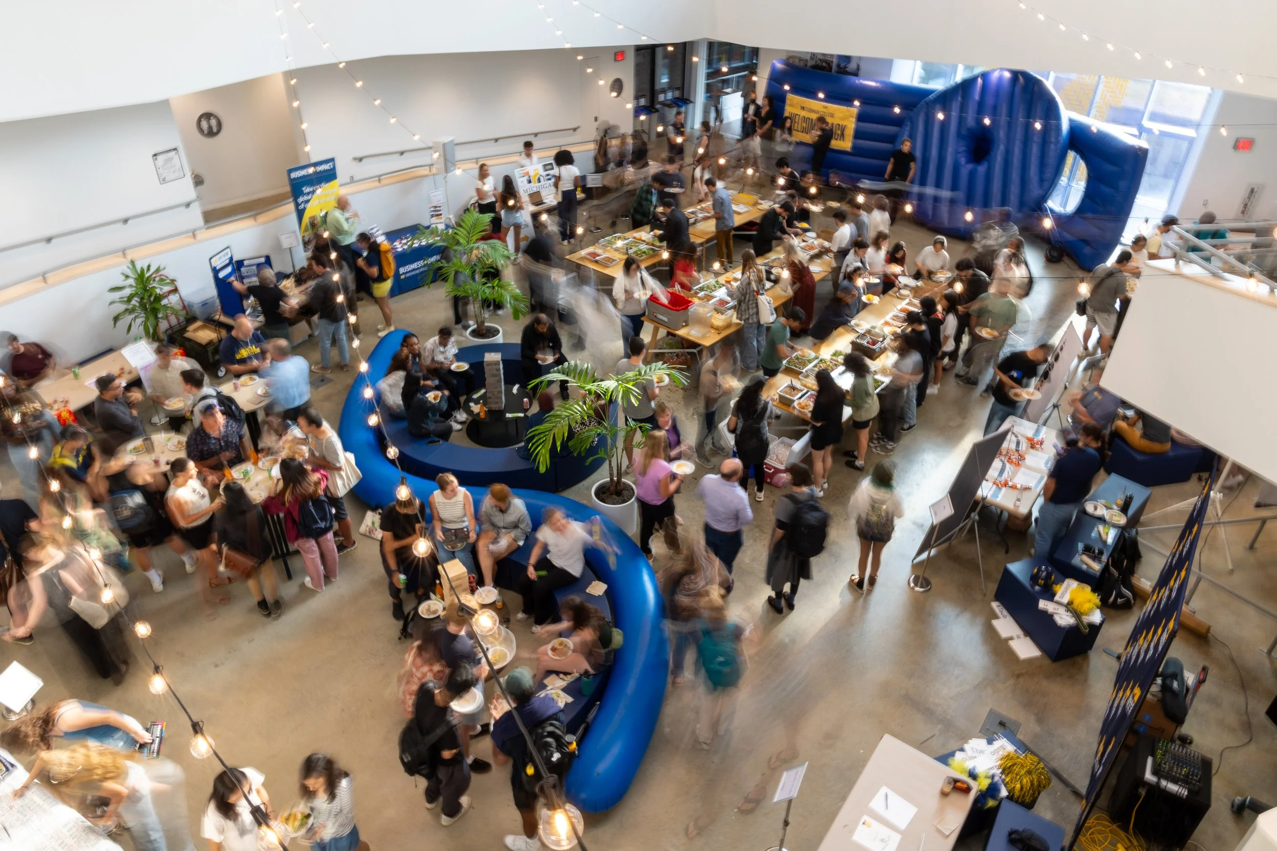 A long exposure of a busy indoor event from the second floor looking down at everyone