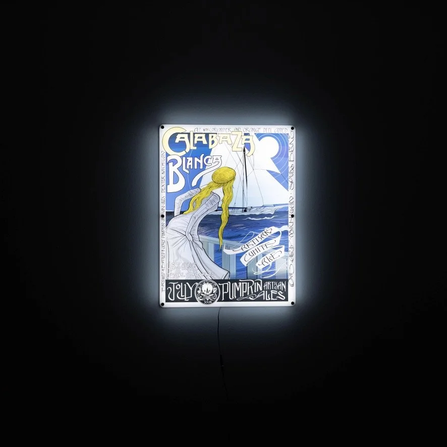 An illuminated LED sign with a woman looking at a sail boat