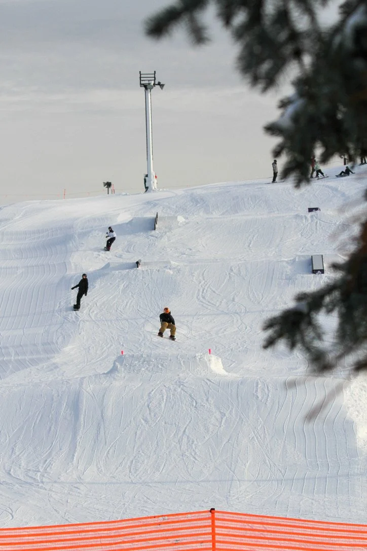 A person mid air coming off a jump in a terrain park at a ski resort