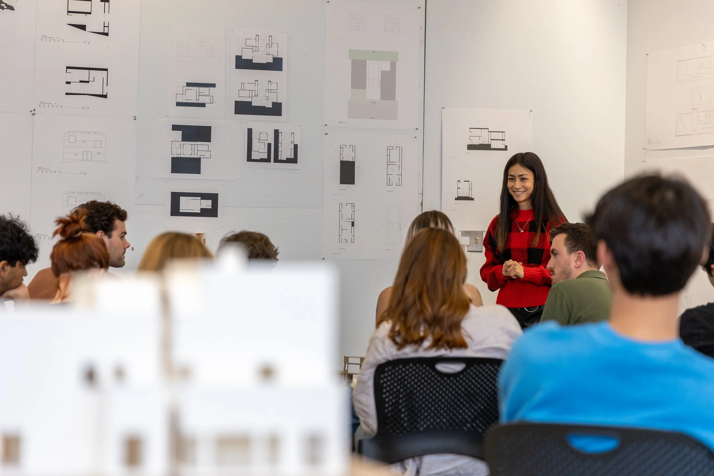 A student smiles while they present their work in front of peers and faculty