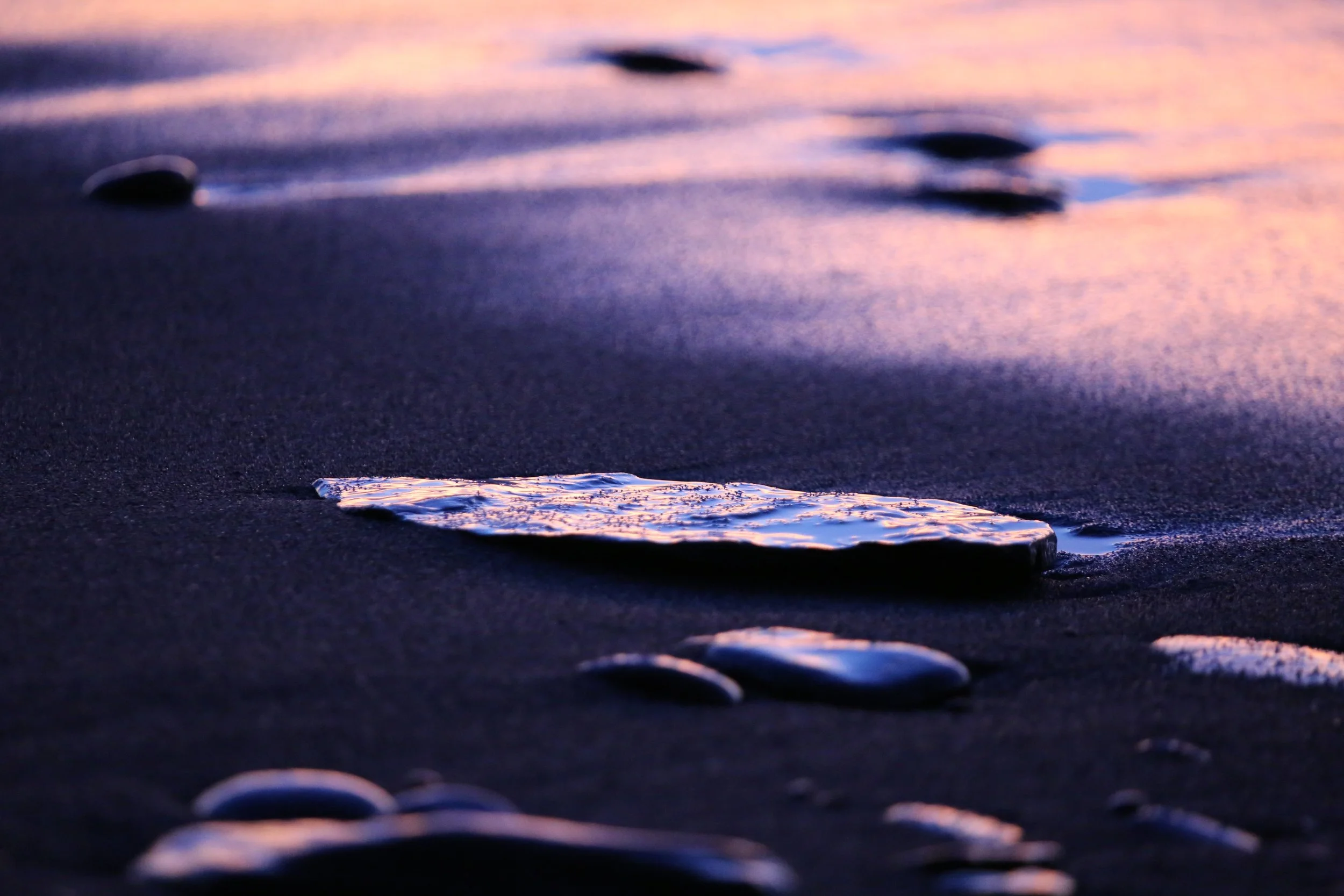 A flat stone on the beach colored vibrantly from the sunset