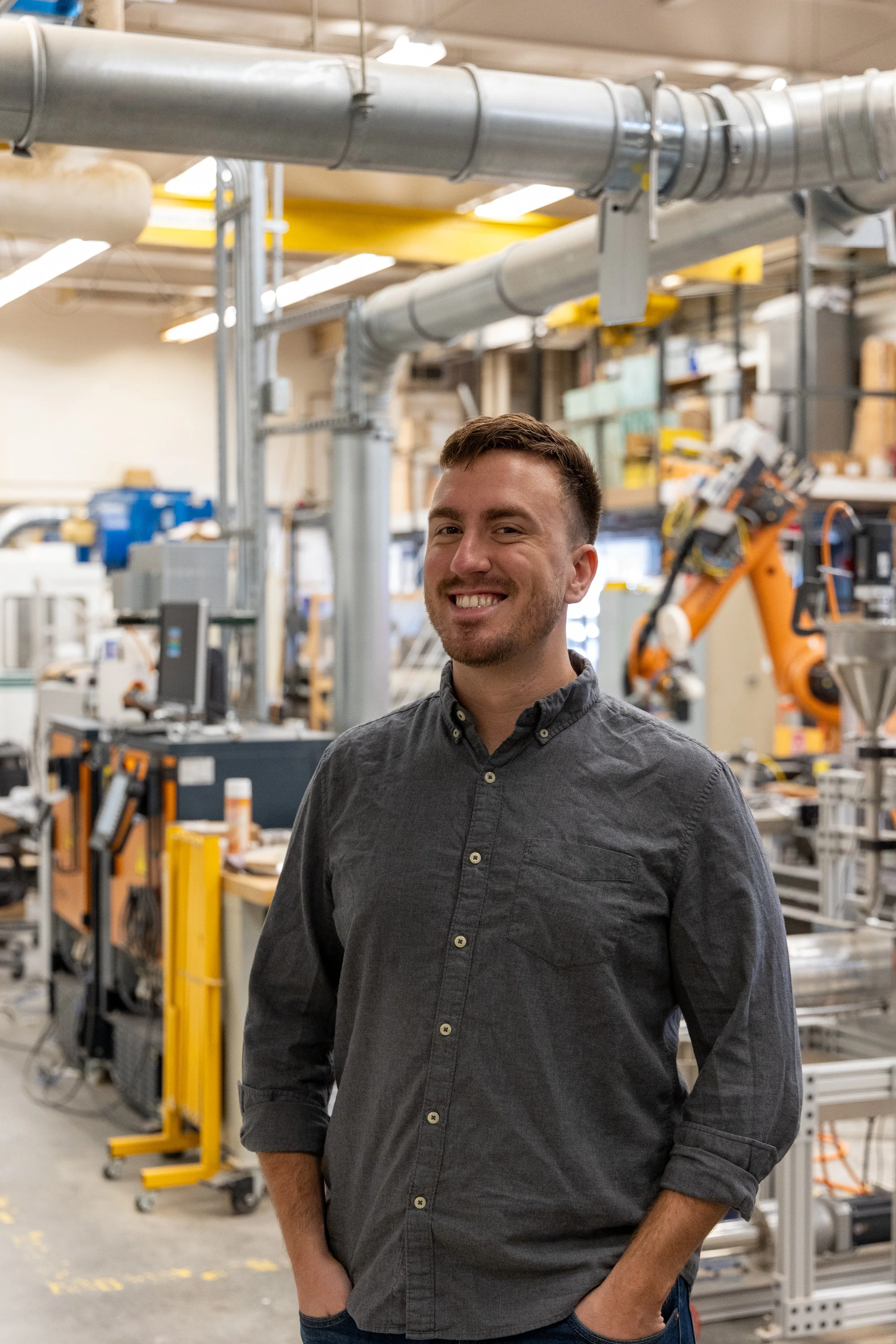 A headshot of a man smiling in an industrial setting