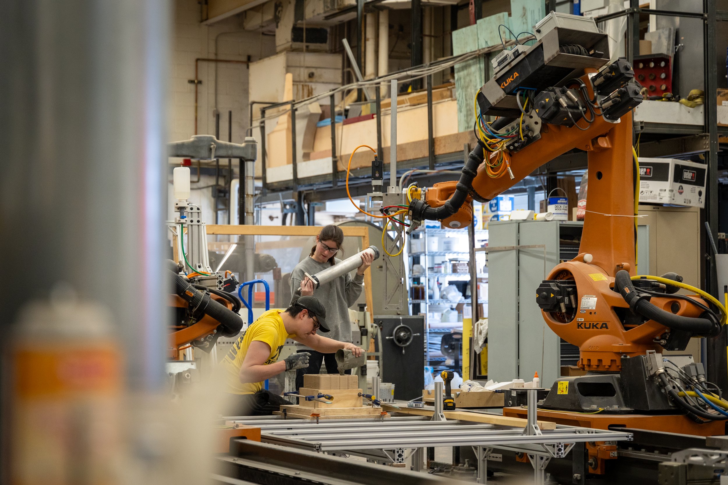 Two students work in a robotic lab on a concrete structure