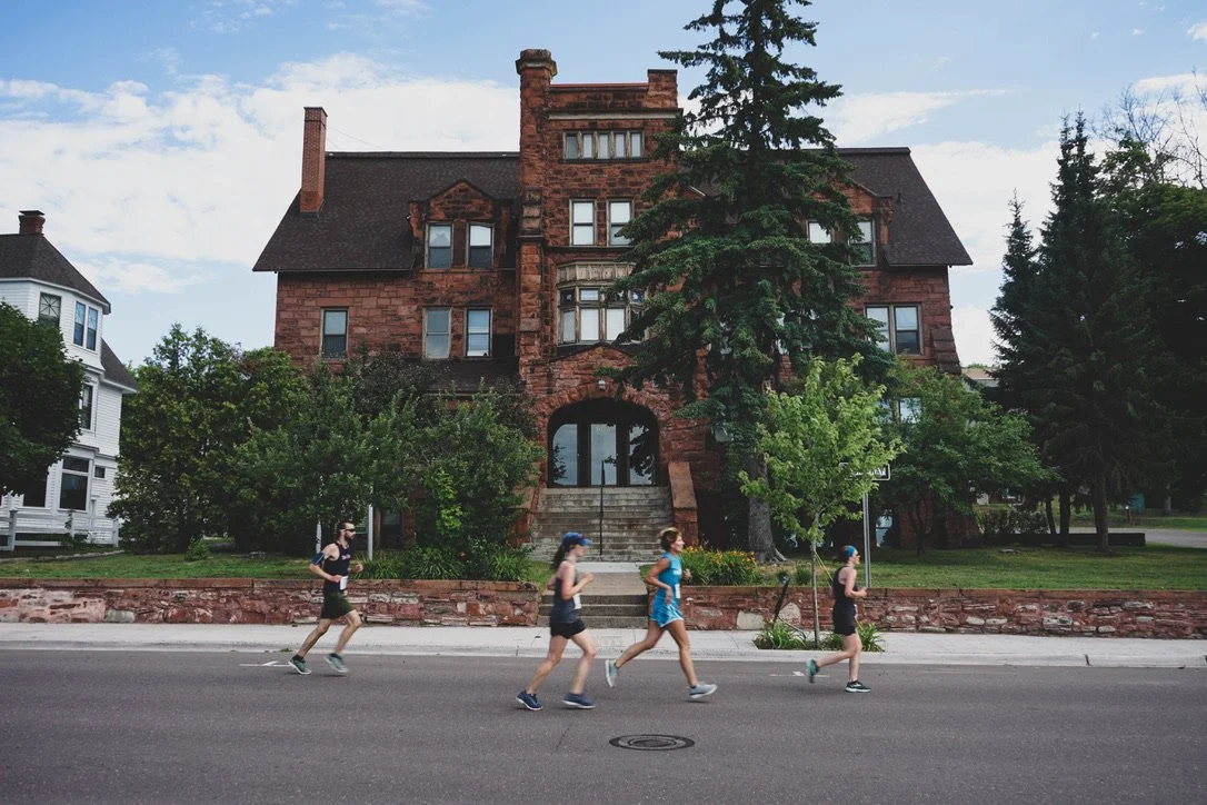 Four runners run in front of a historic building during a race