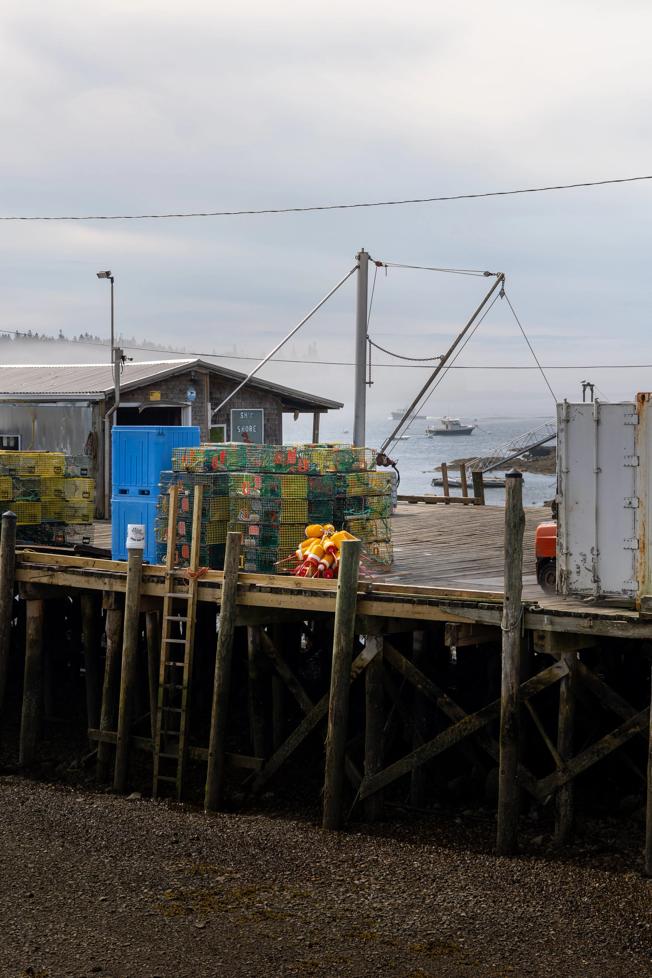 A fishing dock in Maine with crab cages and boats off in the distance