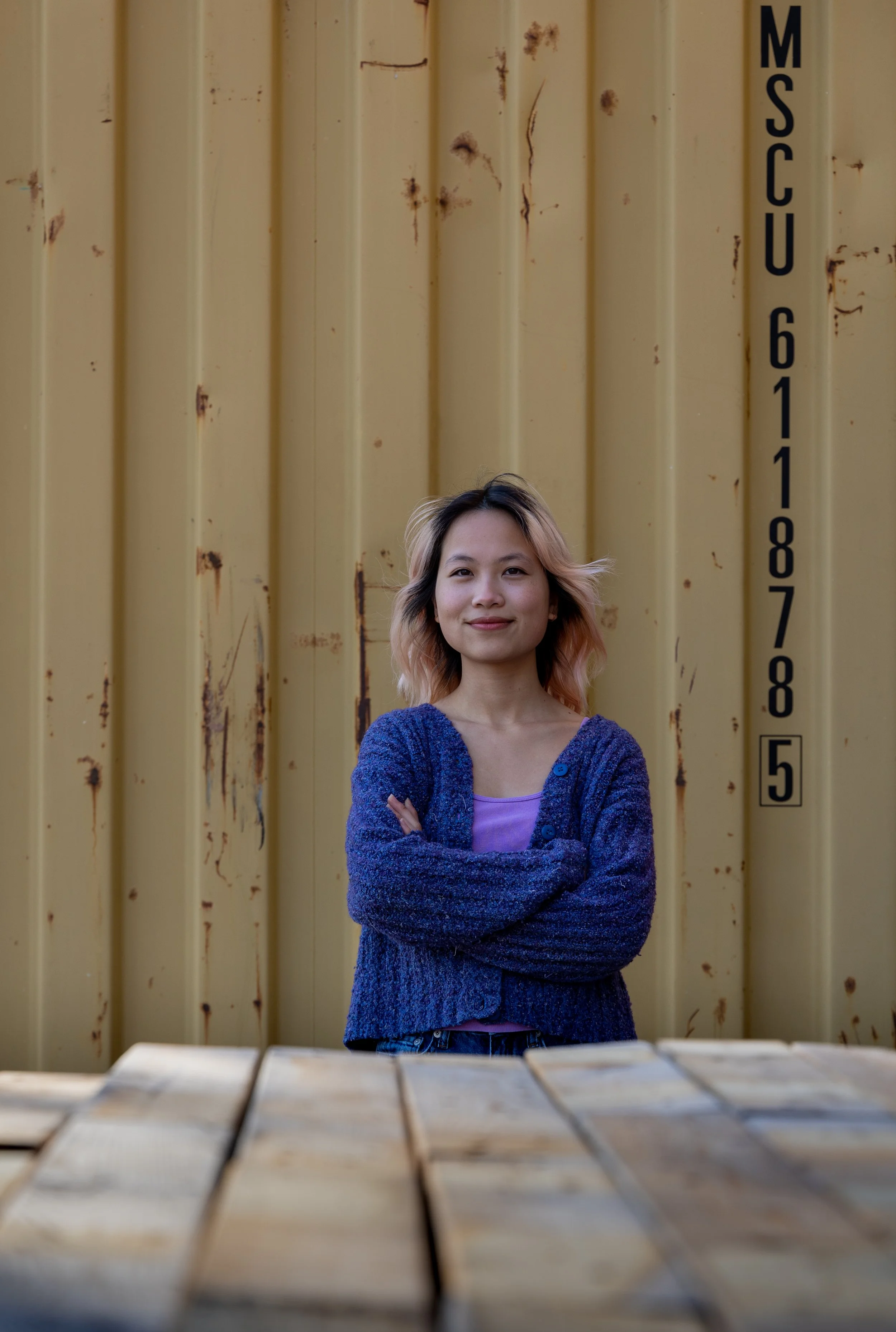 A woman in front of a cargo container poses for a photo 