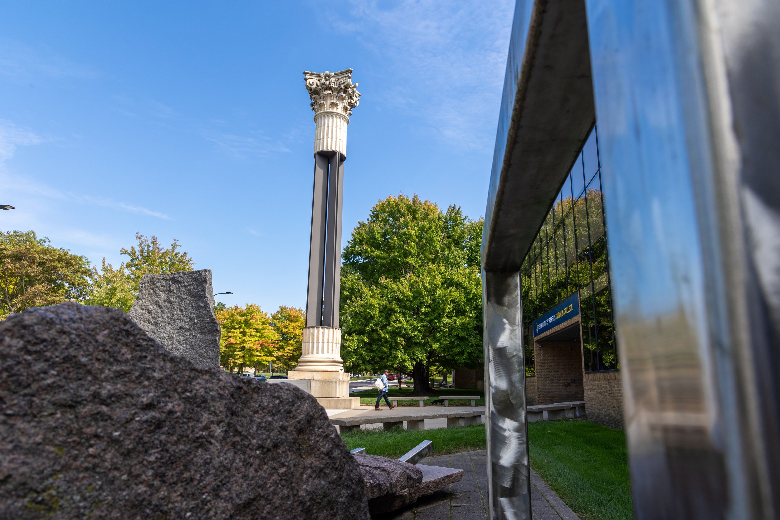 An outoor shot of a column with blue skies and green trees