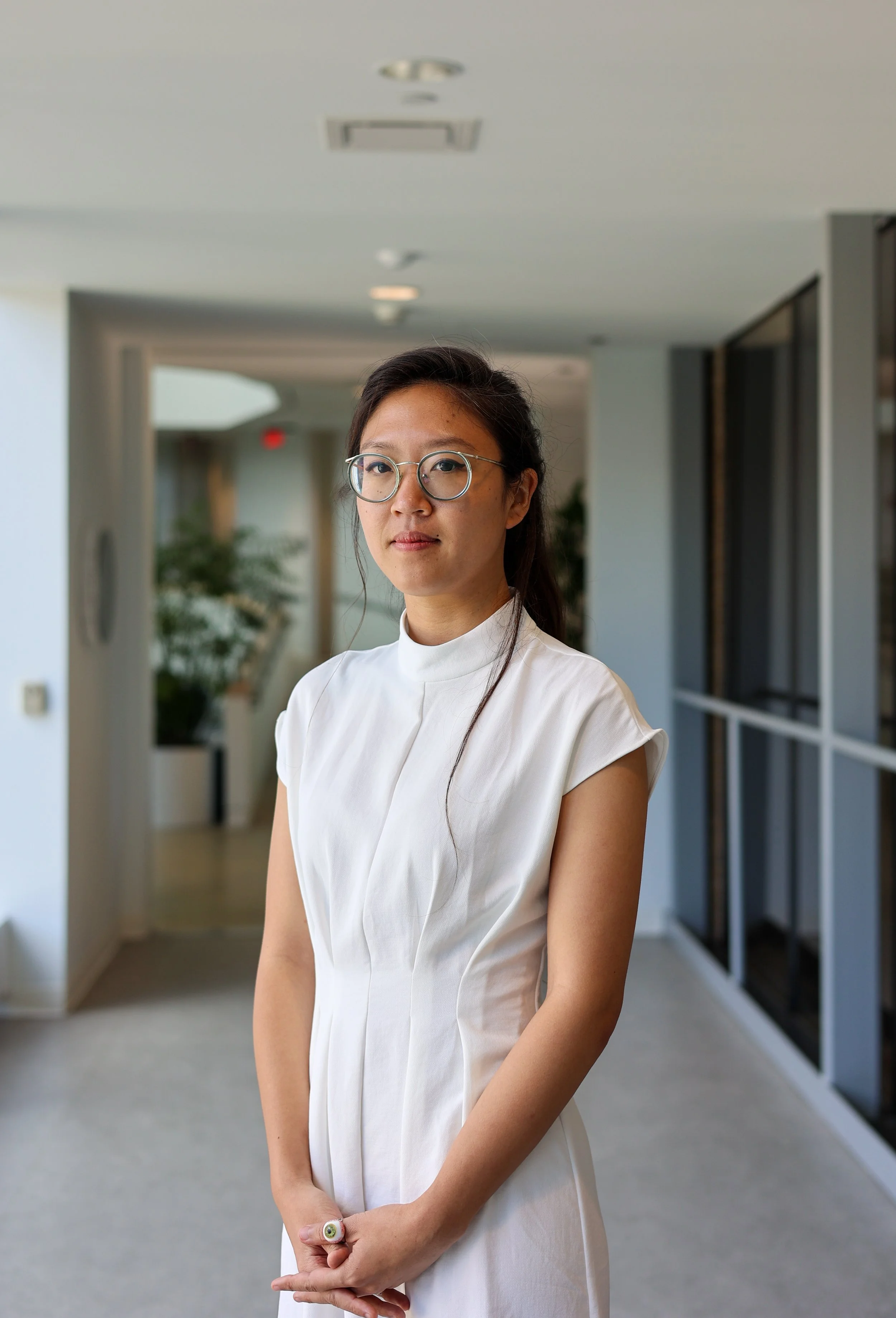 A headshot of a woman in a white dress with a neutral expression