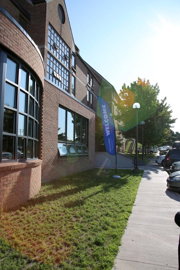The exterior of a building with a blue flag that says "Welcome"
