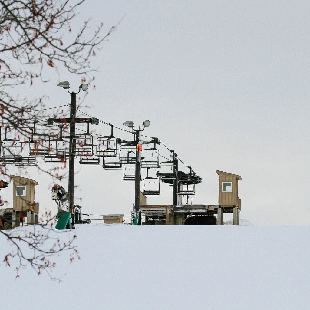 An empty chairlift surrounded by snow