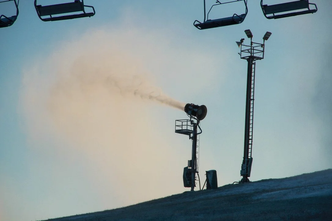 A lone snow maker blows snow onto a mountain