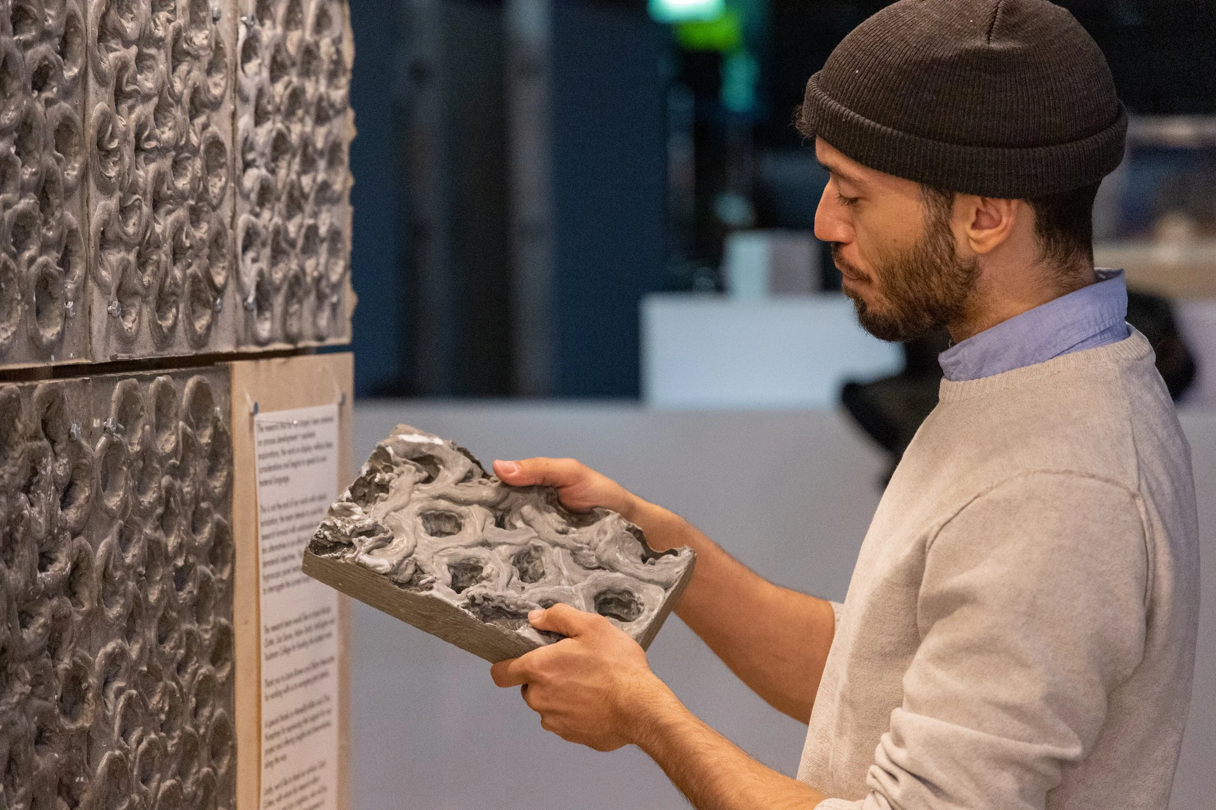 A man wearing a hat explores his work with a concrete slab for his architecture project