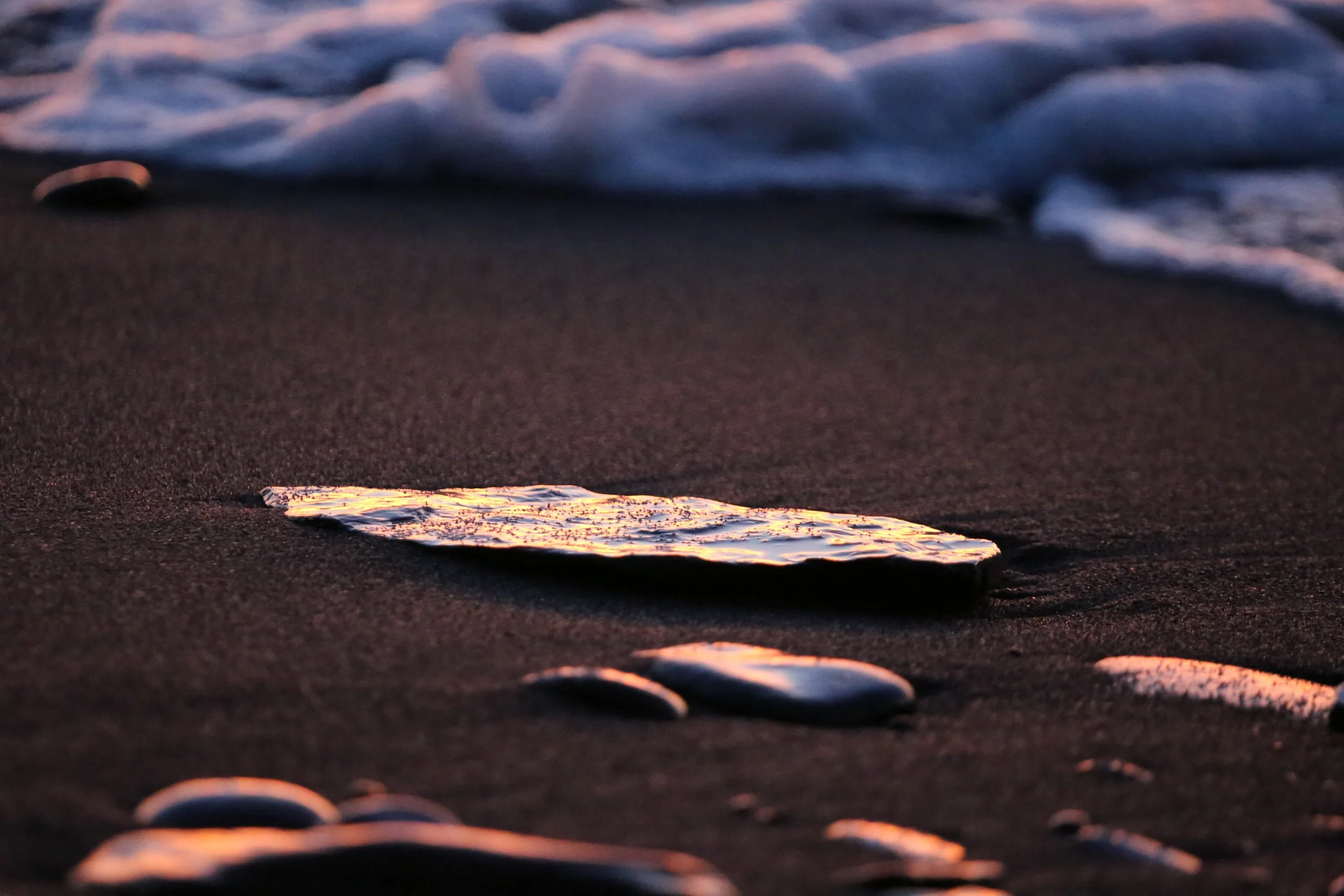 A flat stone on the beach colored vibrantly from the sunset