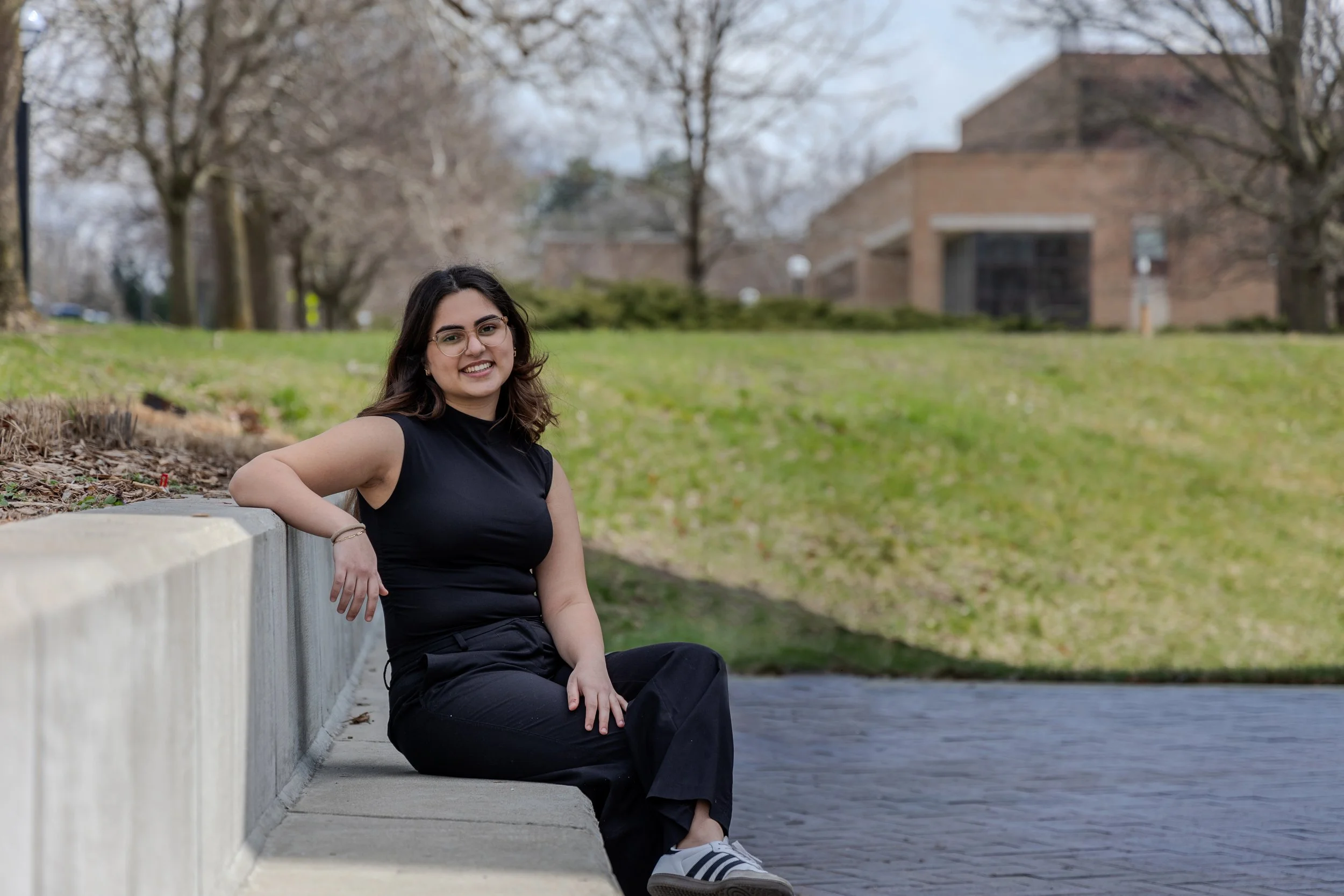 A woman sits on a cement bench smiling for the camera