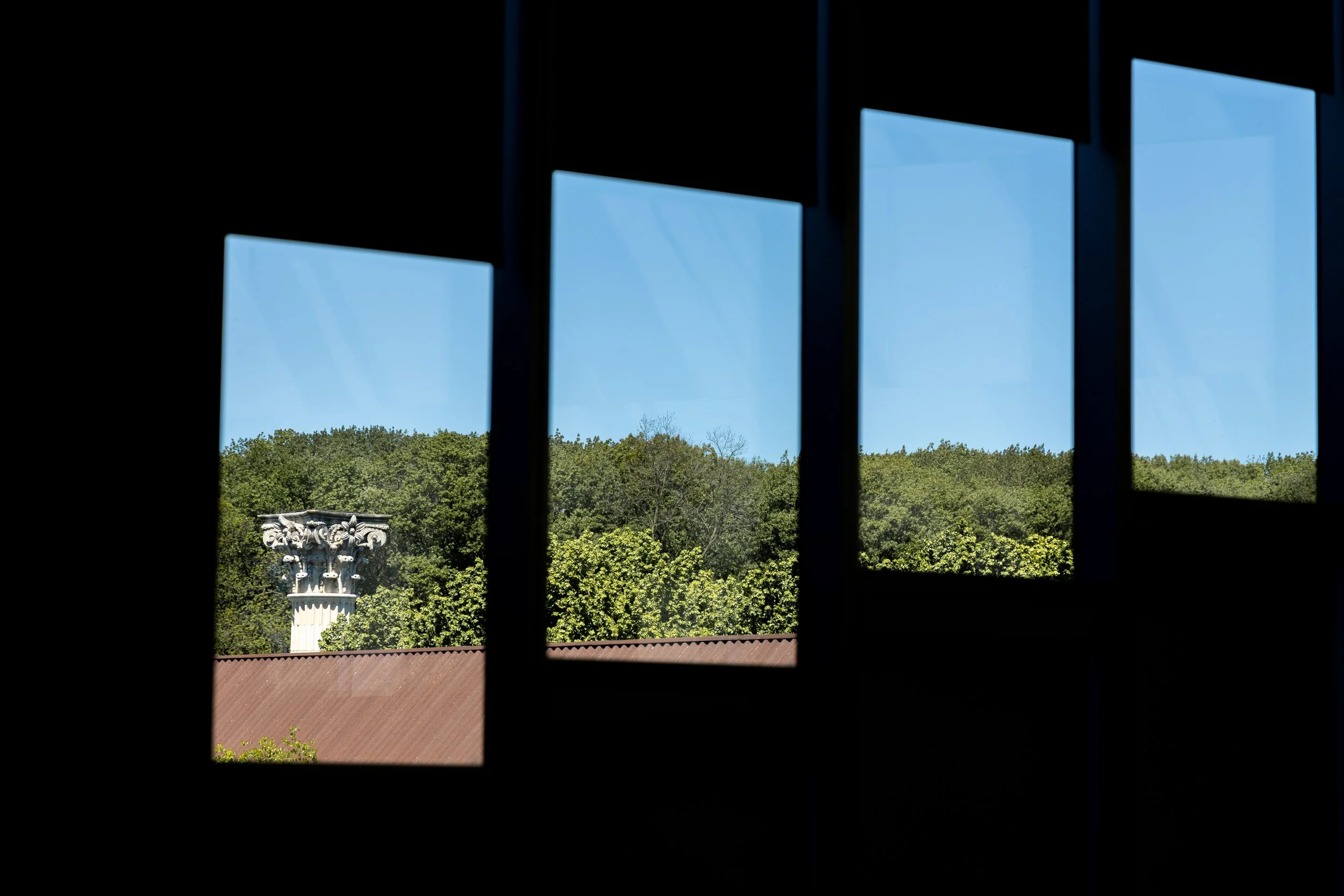 A view of a colum and trees through four panes of windows