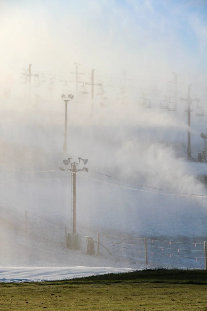 Snow machines blow snow over green grass