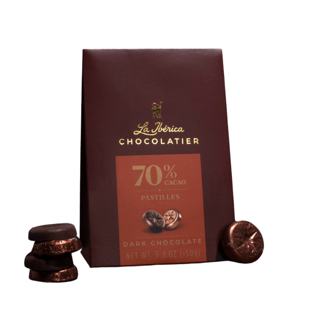 Dark chocolate box labeled 'La Ibérica Chocolatier' with 70% cacao and pastilles, with some pastilles placed next to the box.