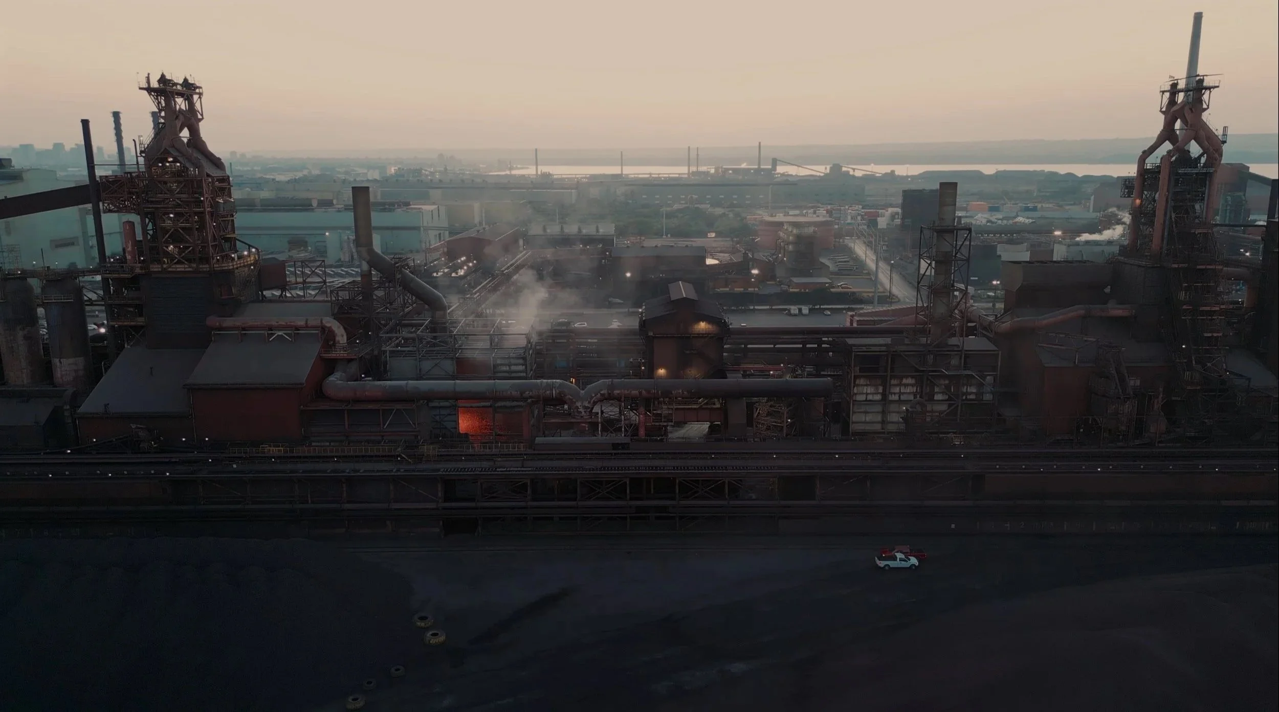 Aerial view of steel plant with glowing furnace and industry in the background