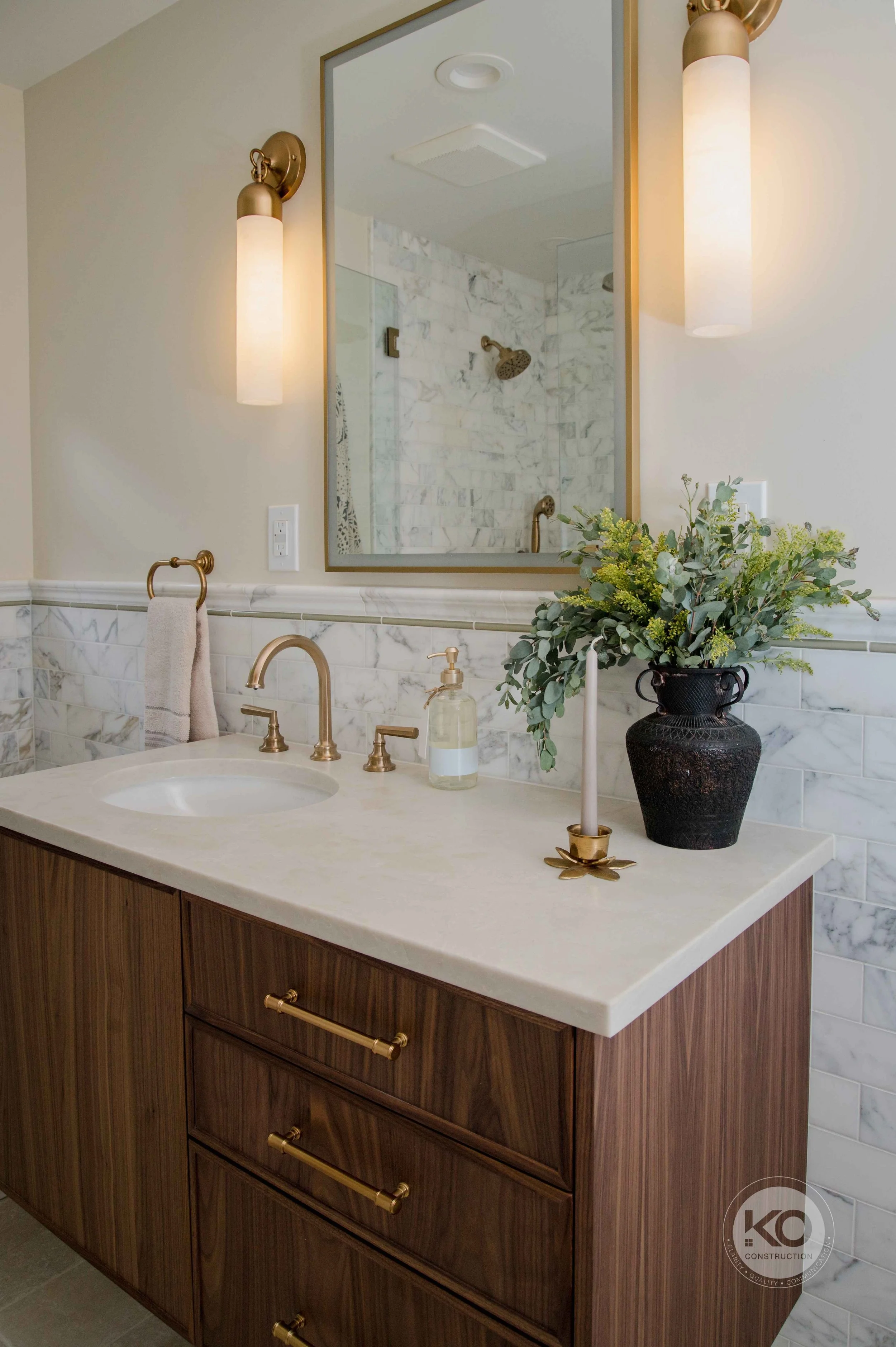 Custom walnut vanity with quartz countertop and brass fixtures in a Federal Way primary bathroom remodel.