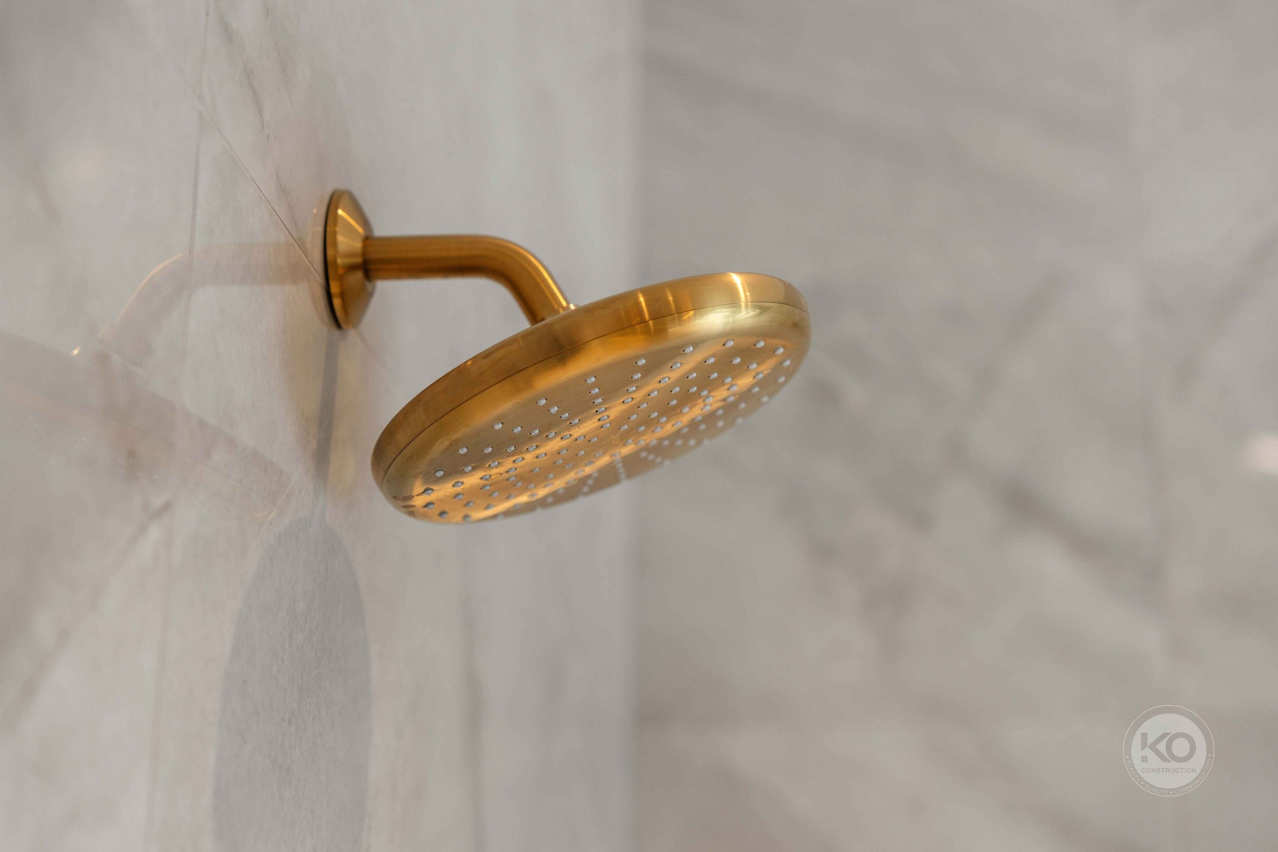 Brass rain shower fixture detail in a luxury bathroom remodel near Tacoma, Washington.