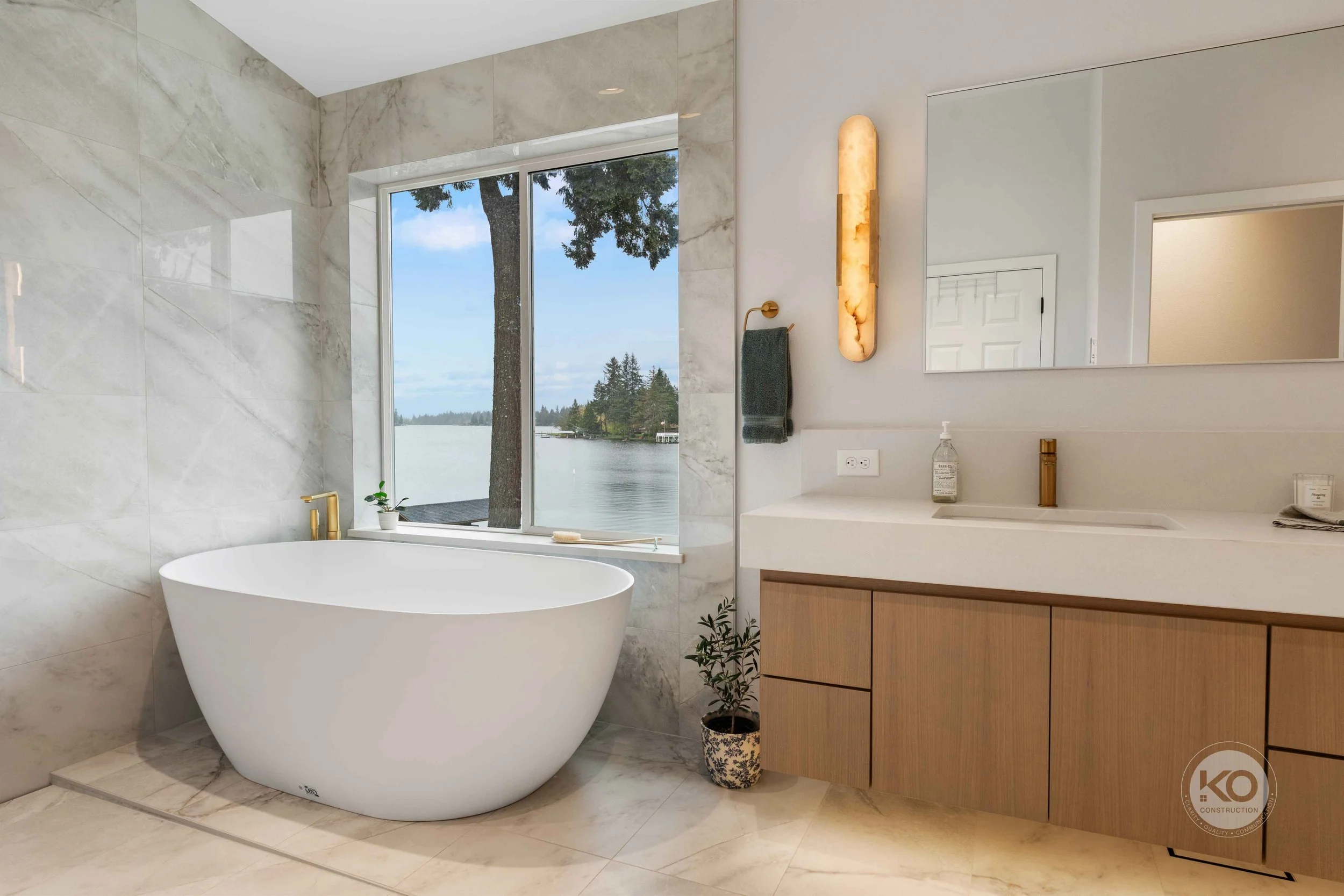 Custom vanity with illuminated mirror and brass fixtures in a Lake Tapps primary bathroom remodel.