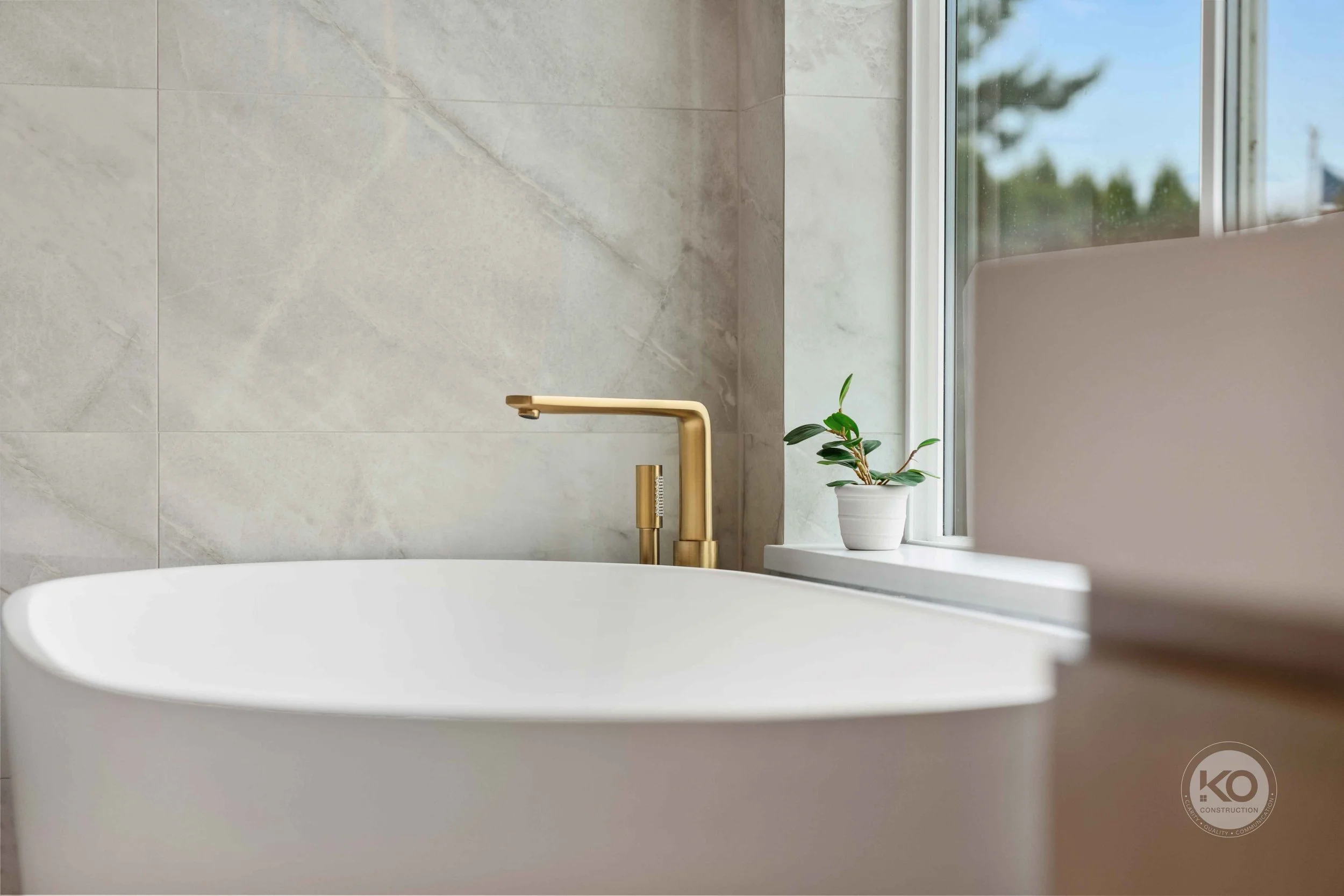 Freestanding soaking tub with brass faucet over in Lake Tapps luxury primary bathroom remodel.