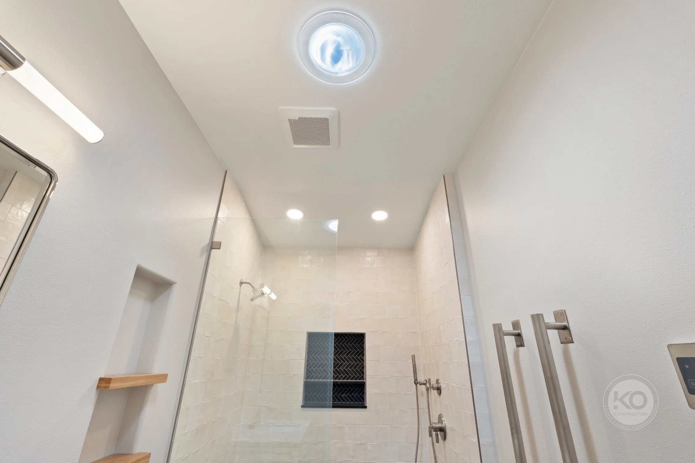 Modern curbless shower with Solatube daylighting and floating wood shelves in a Lake Tapps primary bathroom