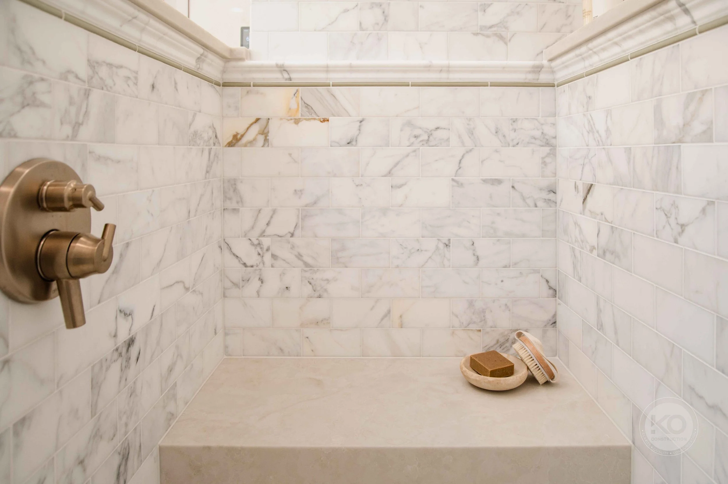 Walk-in shower with Calacatta Gold honed marble walls and integrated bench in a Federal Way bathroom remodel.