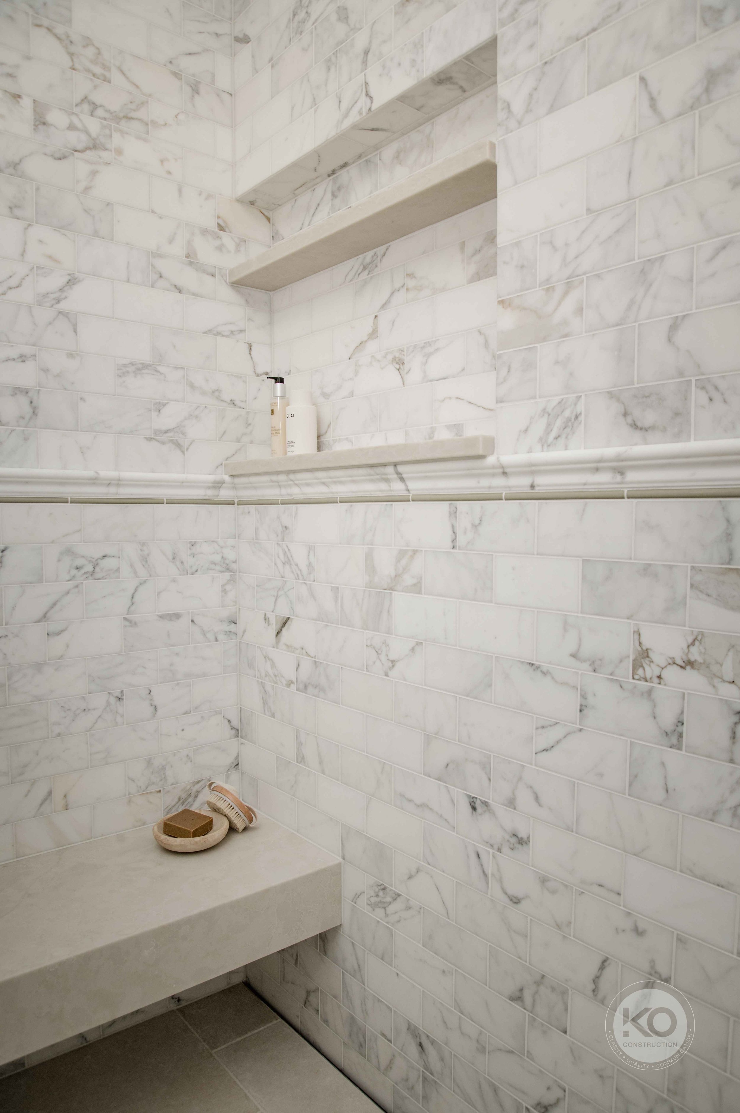 Built-in marble shower bench and recessed storage niche in a custom Federal Way primary bathroom.
