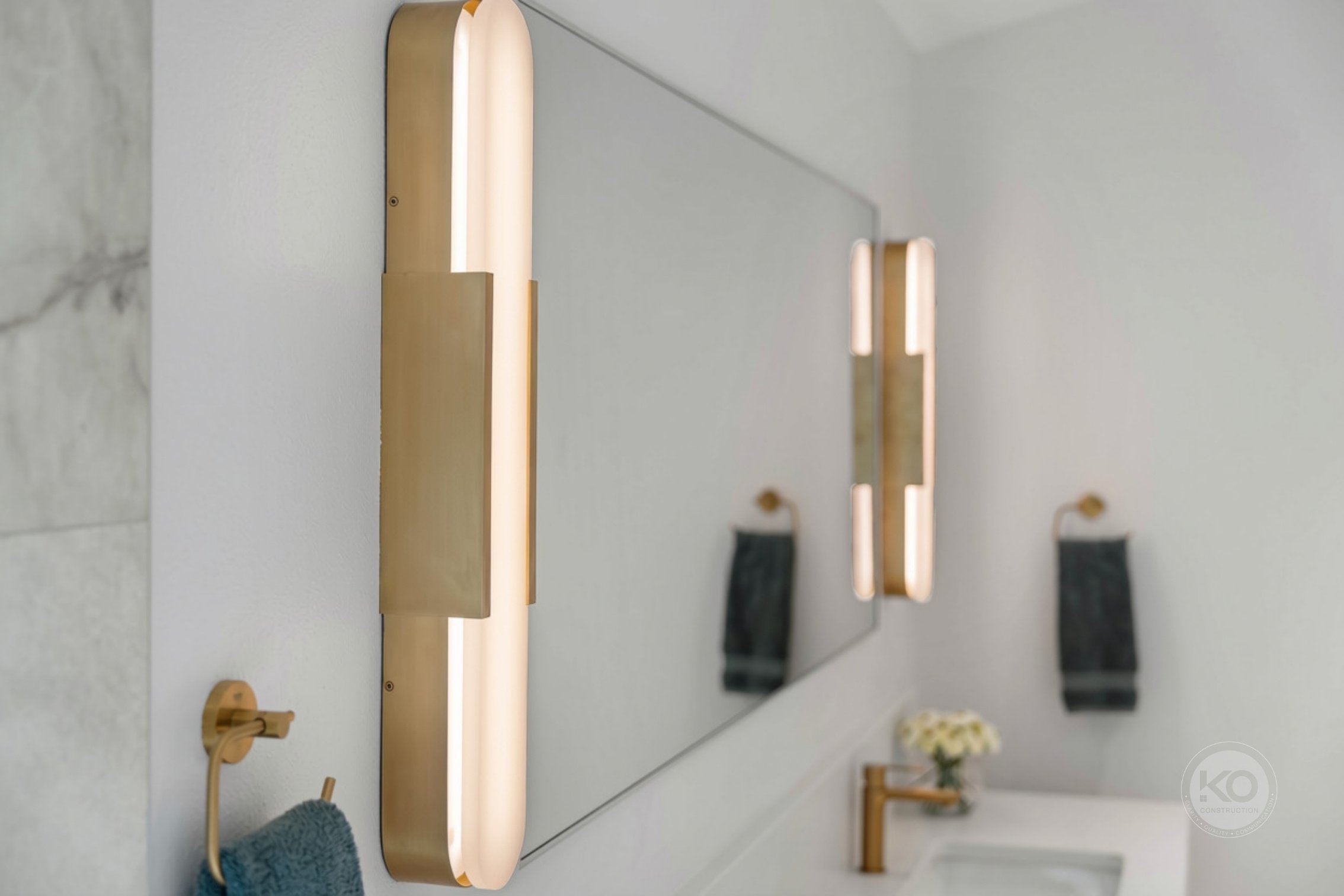 Custom vanity with illuminated mirror and brass fixtures in a Lake Tapps primary bathroom remodel.